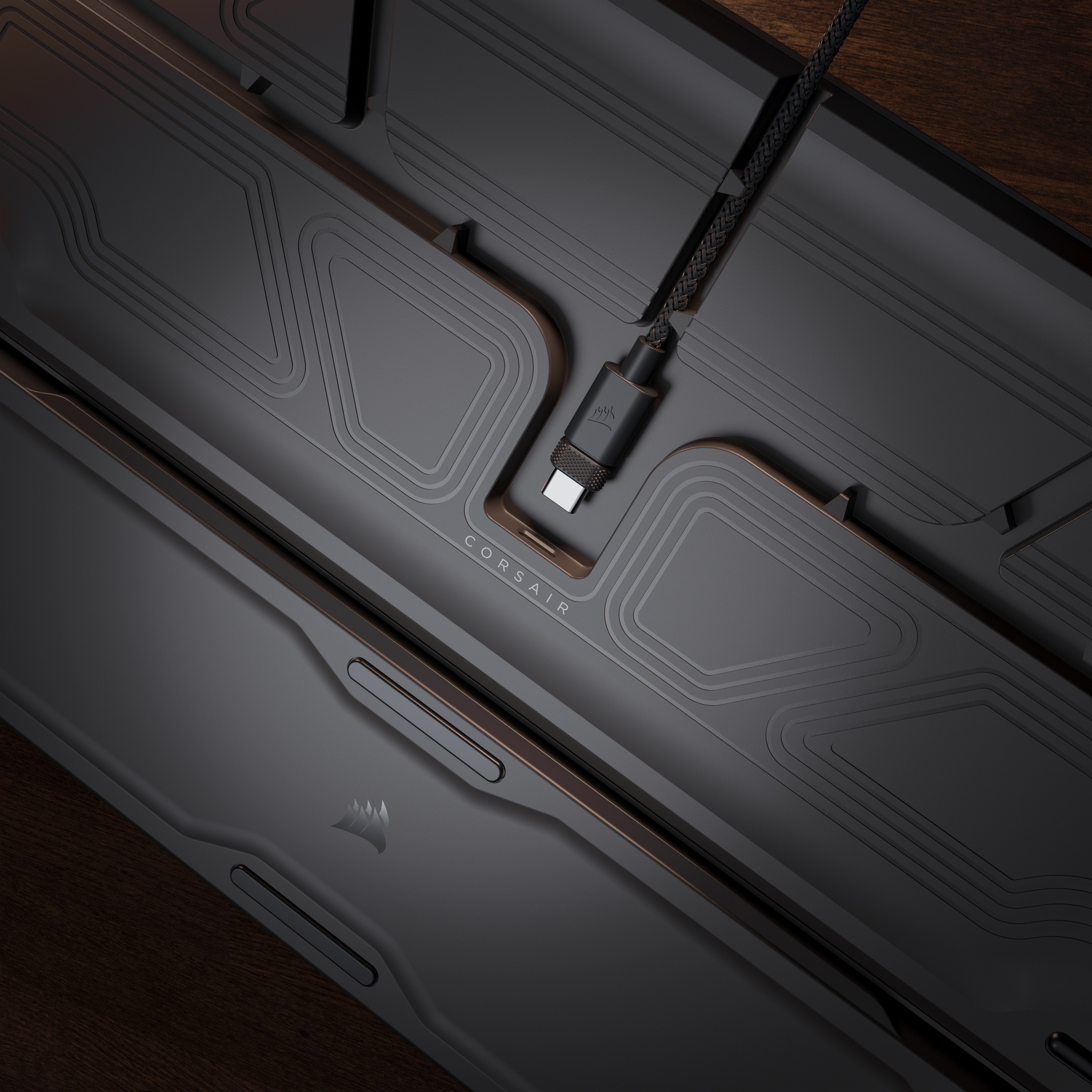 Nahaufnahme einer schwarzen Tastatur mit USB-C-Kabel. Das Corsair-Logo ist sichtbar. Der Hintergrund ist aus Holz.