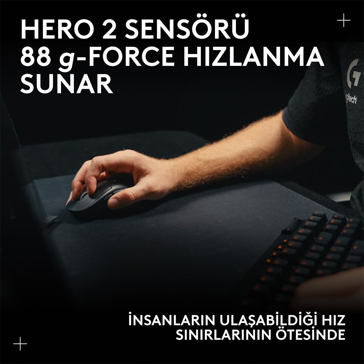 Bir el, siyah bir mouse'u siyah bir ped üzerinde kullanıyor. Bir klavye ve metin görülebilir. Metin şöyle diyor: 'HERO 2 SENSÖRÜ 88 g-FORCE HIZLANMA SUNAR'.