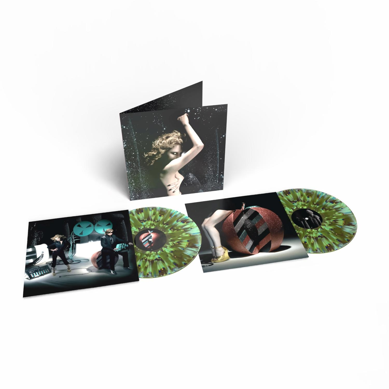 Ein Vinyl-Schallplattenset wird angezeigt. Es enthält Albumcover mit einer Frau und zwei Männern sowie grüne und braune Vinyl-Schallplatten. Weißer Hintergrund.