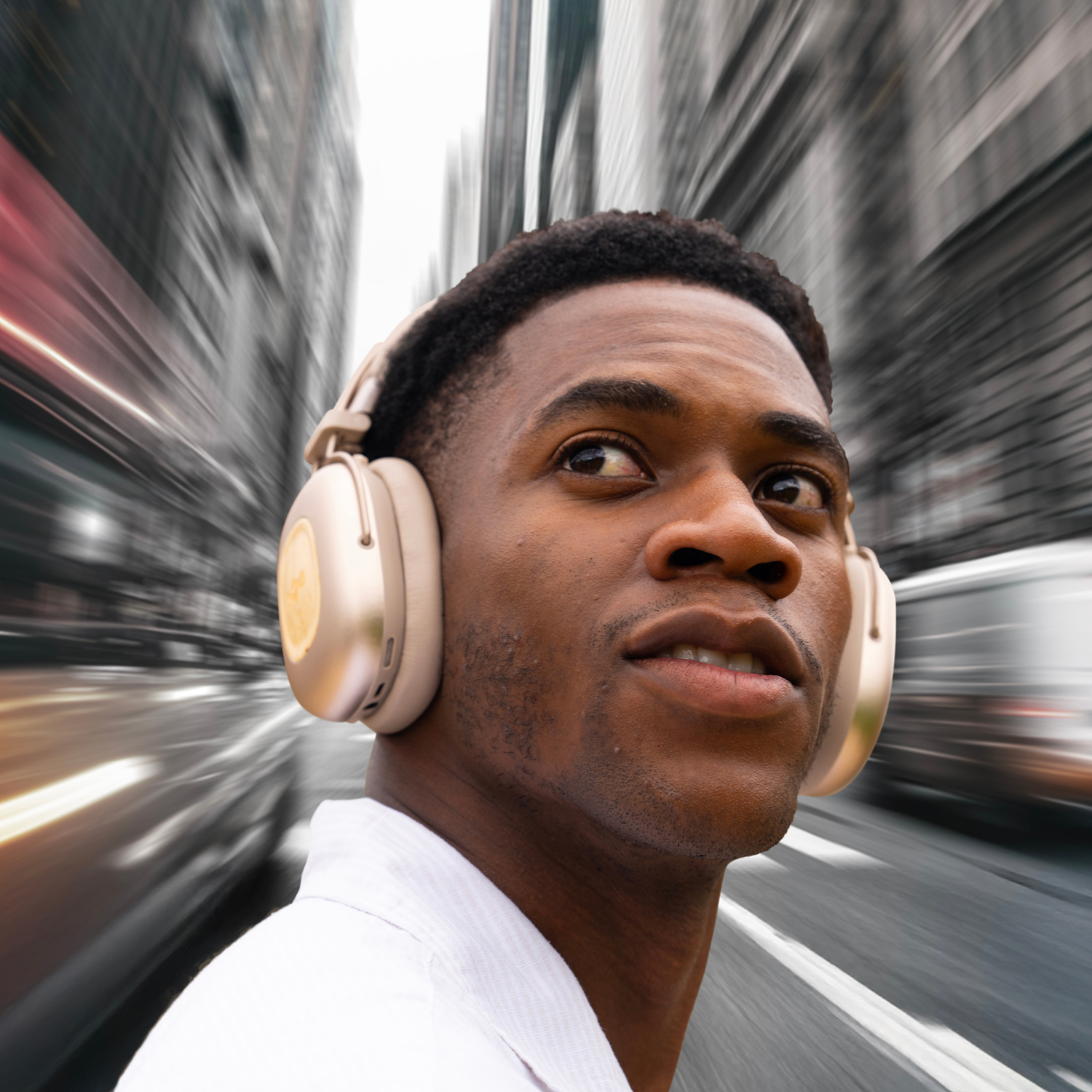 Un homme portant un casque regarde en l'air dans une rue de la ville. Les bâtiments sont flous en arrière-plan, suggérant le mouvement.