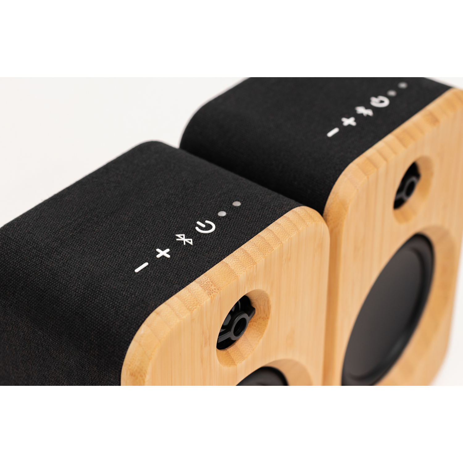 Twee houten luidsprekers met zwarte bovenkanten. De luidsprekers hebben volume-, stroom- en bluetooth-bedieningspictogrammen. De achtergrond is effen wit.