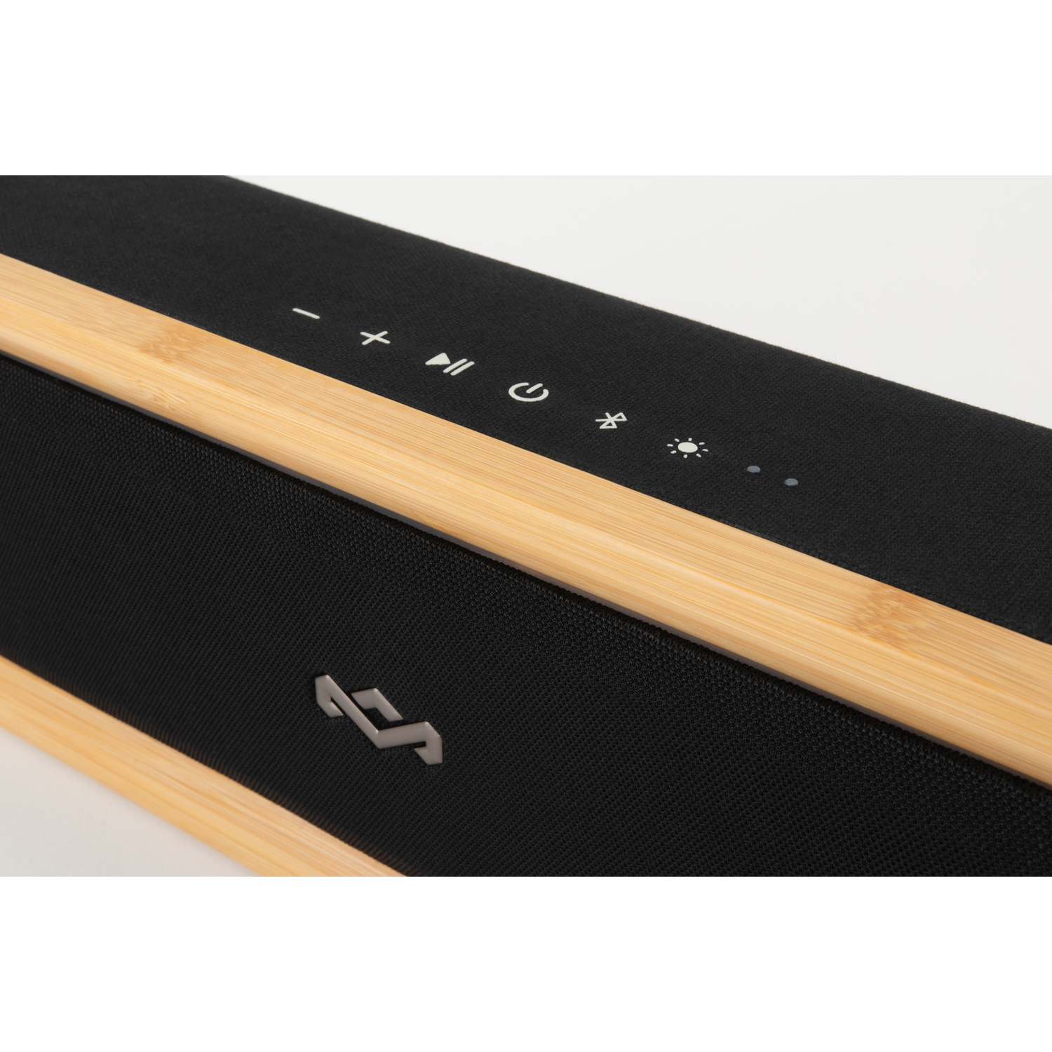 Close-up van een zwarte soundbar met houten frame. Het heeft bedieningsknoppen en een verlicht logo. De achtergrond is wit.