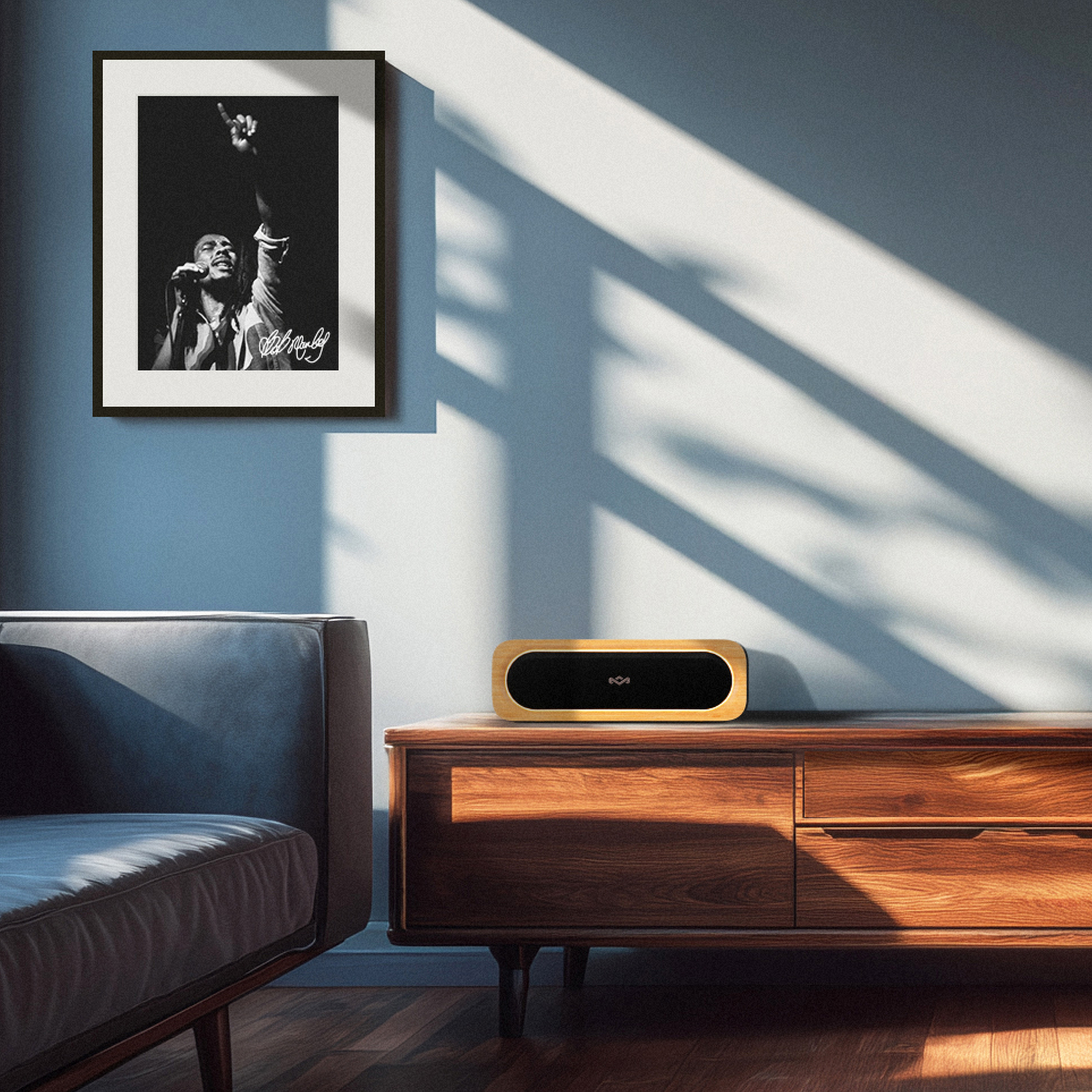 Een kamer met een zwart-wit foto van Bob Marley, een houten kast en een luidspreker. Zonlicht creëert schaduwen op de muur.