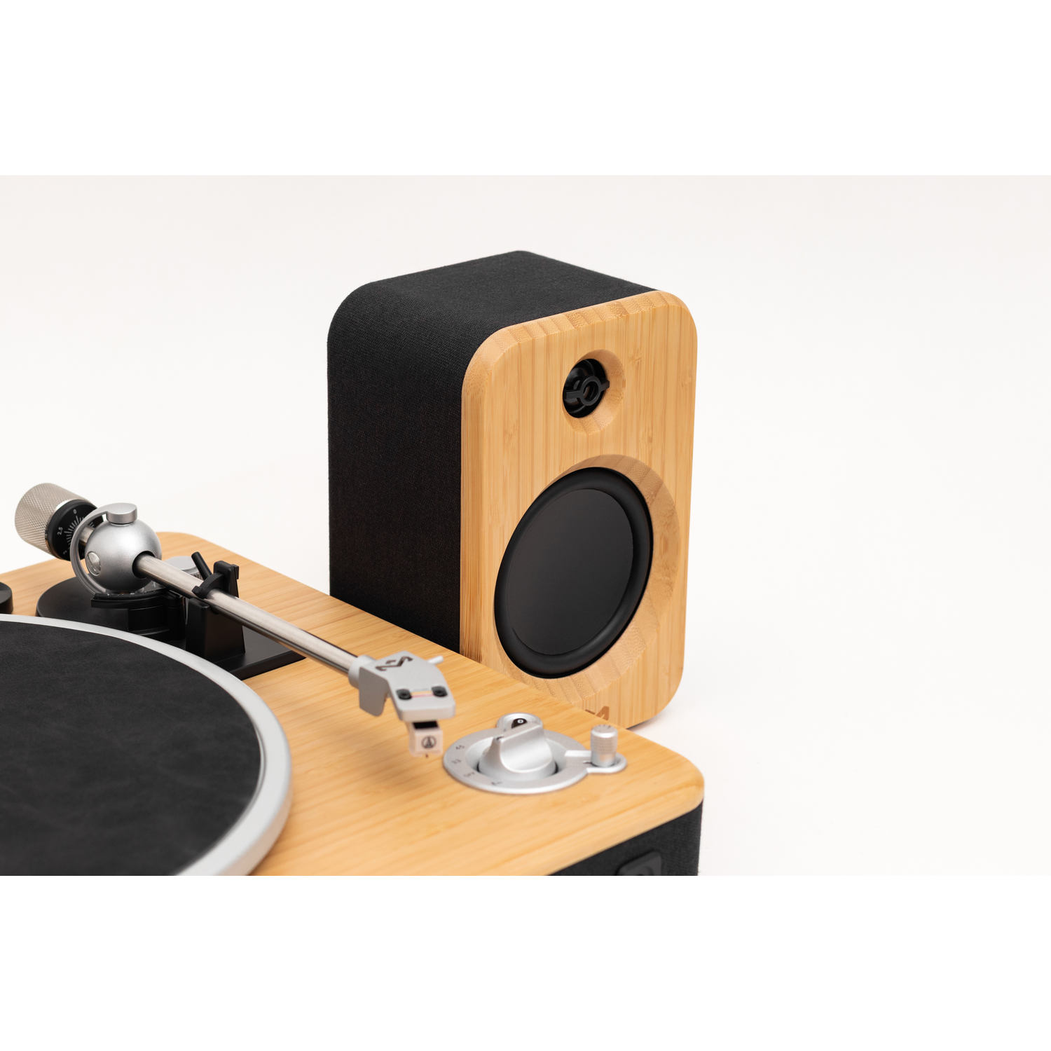 A wooden turntable and speaker set. The turntable is light wood with a black record. The speaker is bamboo with a black speaker.