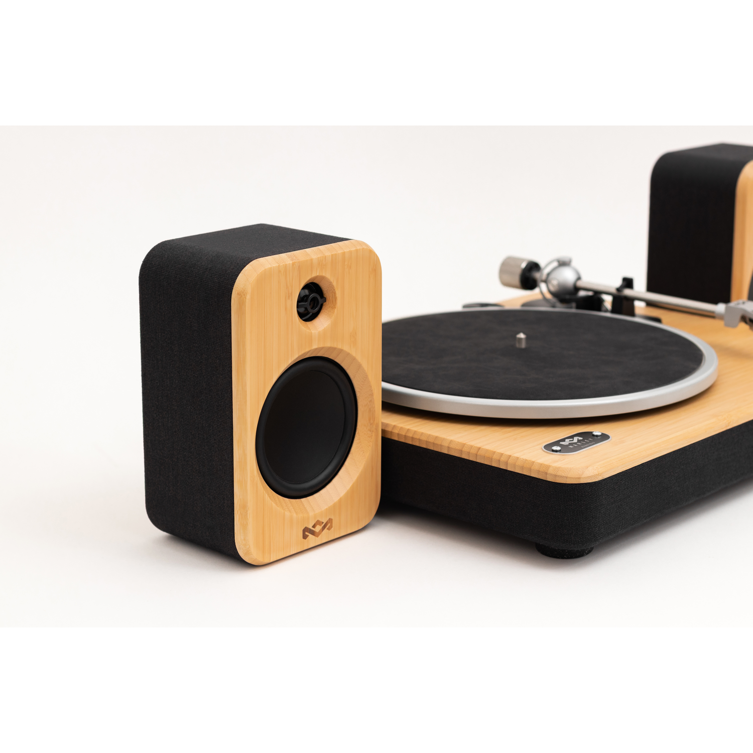 A bamboo speaker and turntable are set against a white backdrop. The speaker is black and bamboo, with a round speaker.