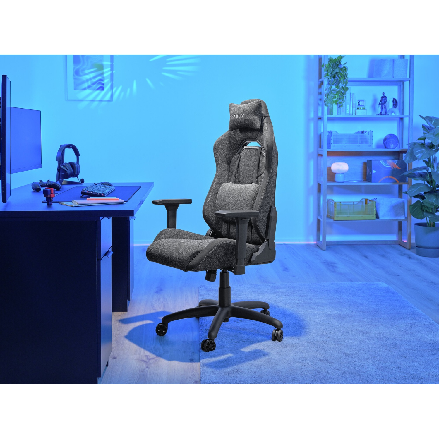 Sedia da gaming in una stanza con scrivania, monitor, cuffie e libreria sullo sfondo. Illuminazione blu.