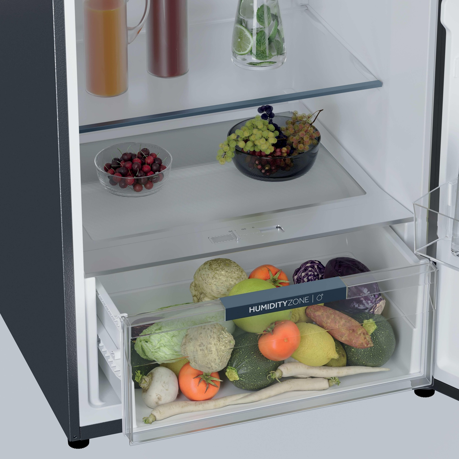 All'interno di un frigorifero: frutta, verdura e bevande sono conservate. Un cassetto mostra vari prodotti. Sono visibili anche vasi e bicchieri sugli scaffali.