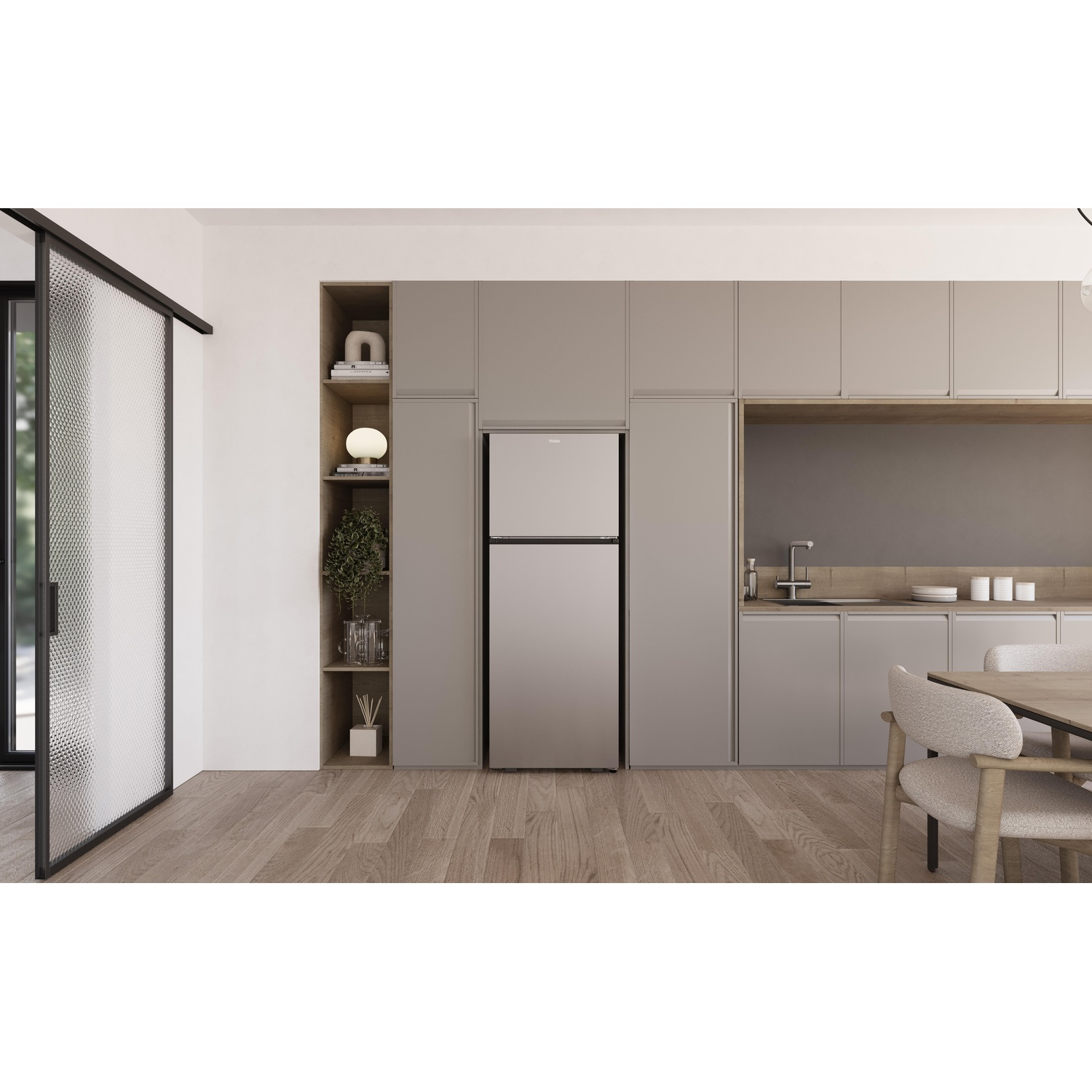 Una cucina moderna con un frigorifero argentato. Sono visibili pavimenti in legno, armadi, un tavolo da pranzo con sedie e una porta a vetri.