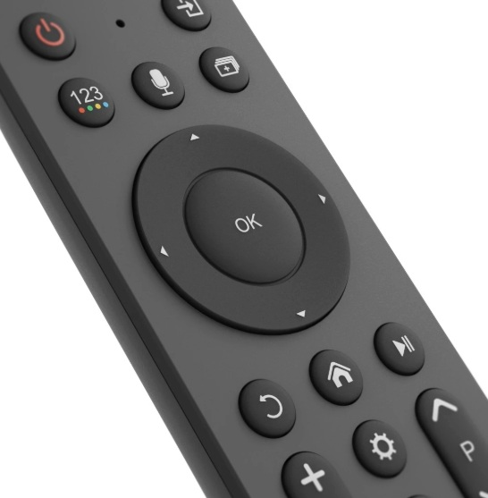 Zbliżenie czarnego pilota z różnymi przyciskami, w tym zasilania, mikrofonu, home i kontrolkami kierunkowymi.