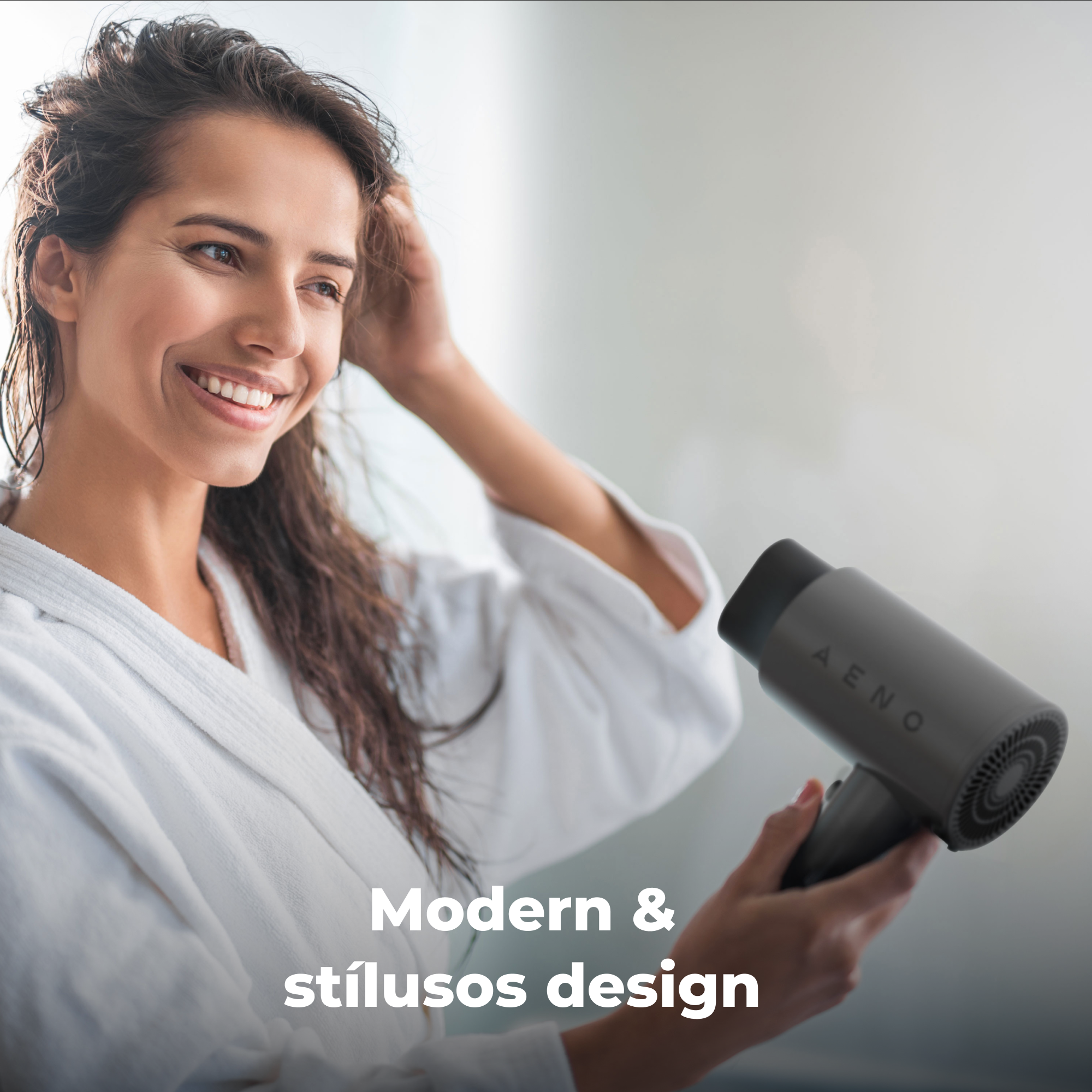 Egy fehér köntösös nő mosolyog, egy szürke hajszárítót tart, rajta az 'AENO' felirattal.
