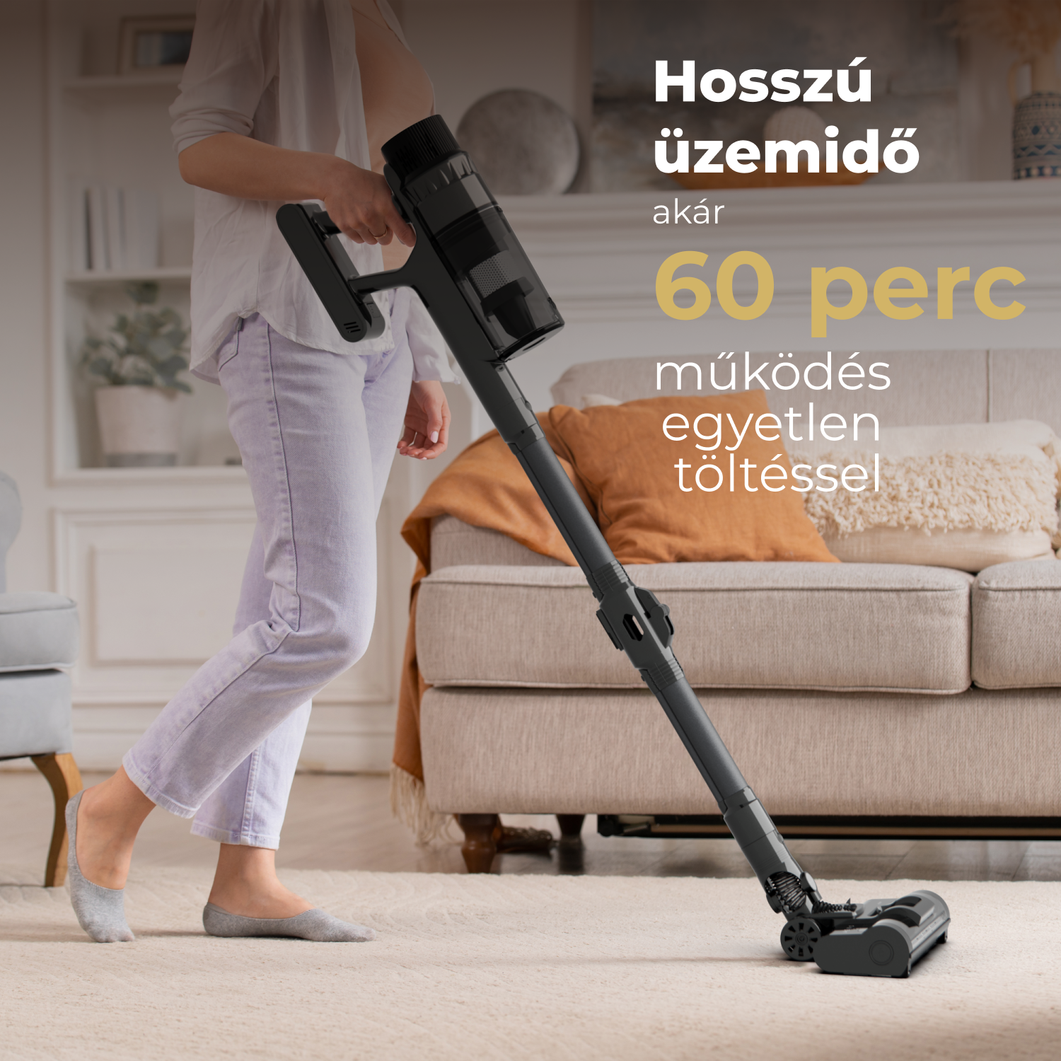 Egy személy, aki egy szőnyeget porszívózik egy fekete, vezeték nélküli porszívóval. A háttérben egy kanapé, egy narancssárga párna és szöveg látható.
