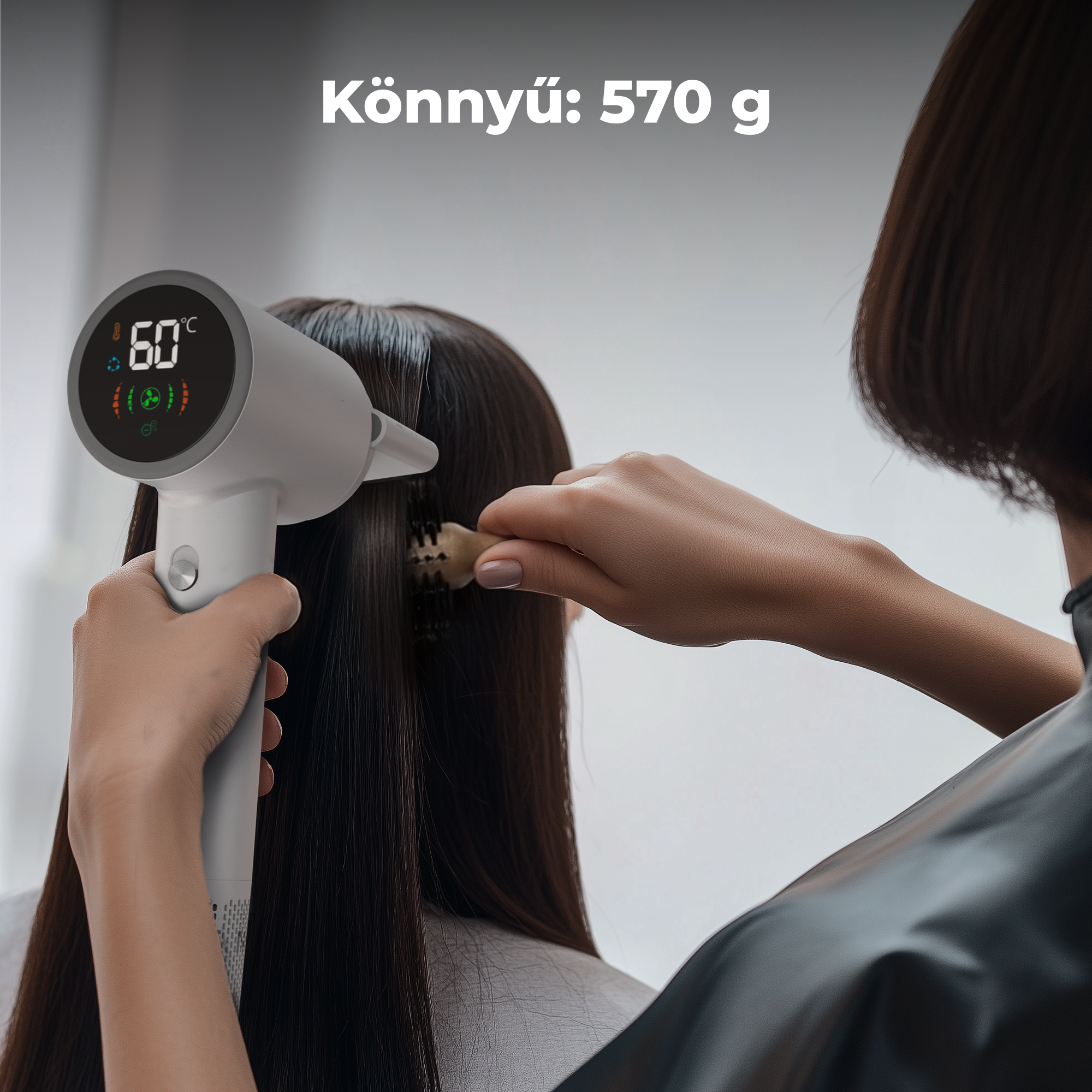 Egy személy hajat formáz hajszárítóval. A hajszárító 60 Celsius fokot mutat. A tetején lévő szöveg: Könnyű: 570g.
