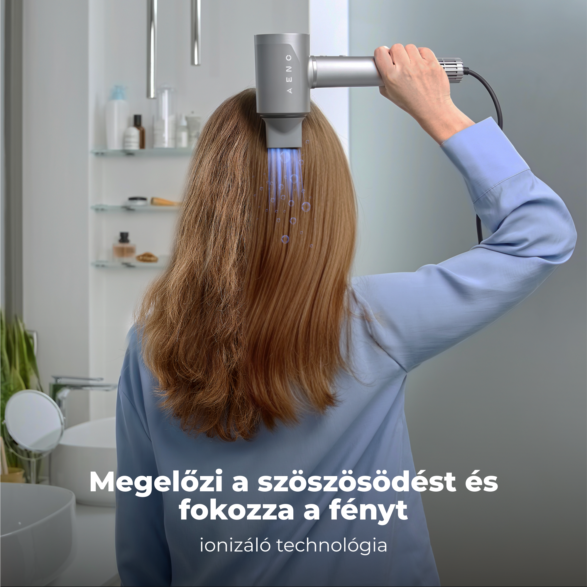 Egy nő egy ezüst hajszárítót használ a hajára. A hajszárító kék fényt bocsát ki. A háttérben egy fürdőszoba látható.