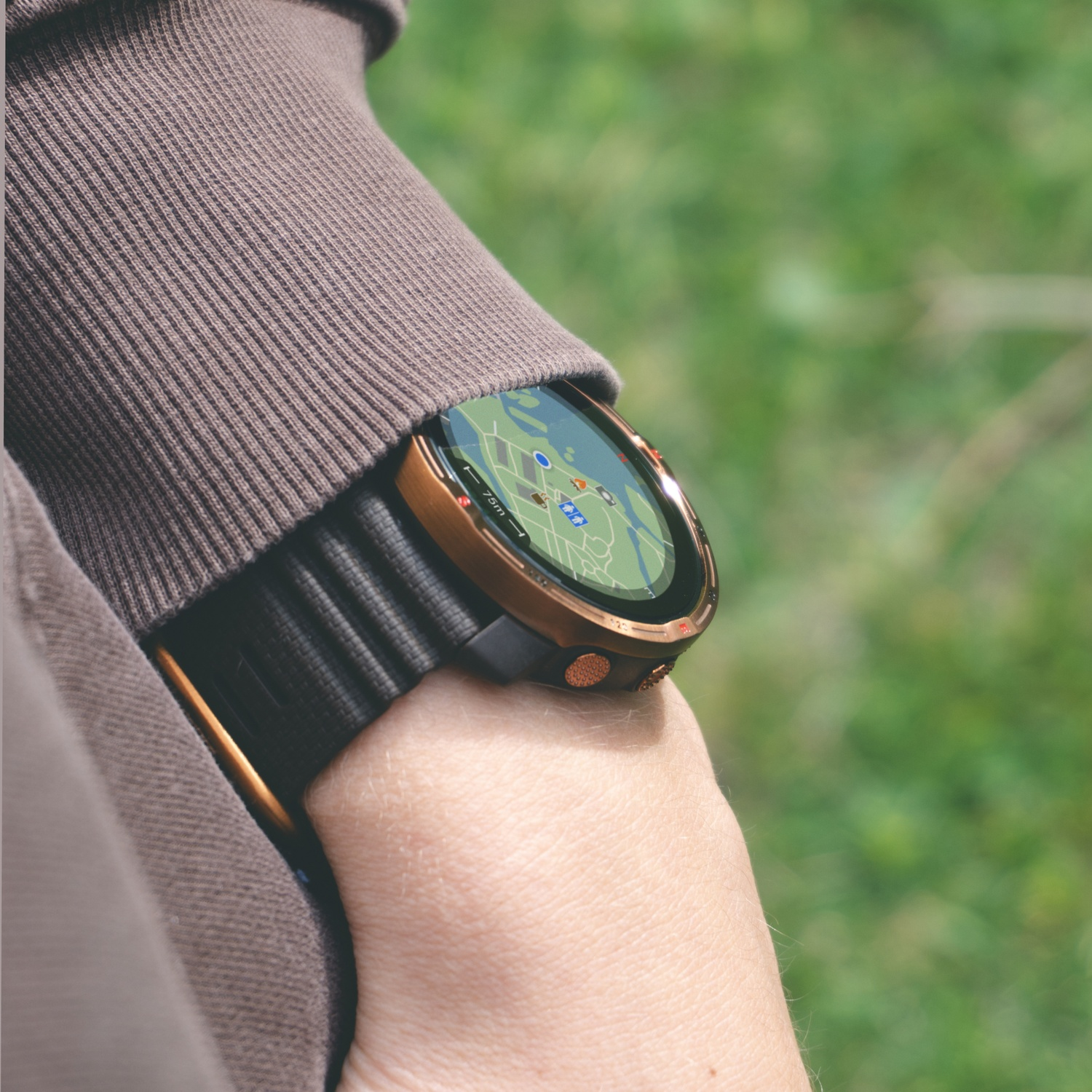 Une personne porte un sweat-shirt marron et une montre connectée avec une carte au poignet. L'arrière-plan est vert flou.