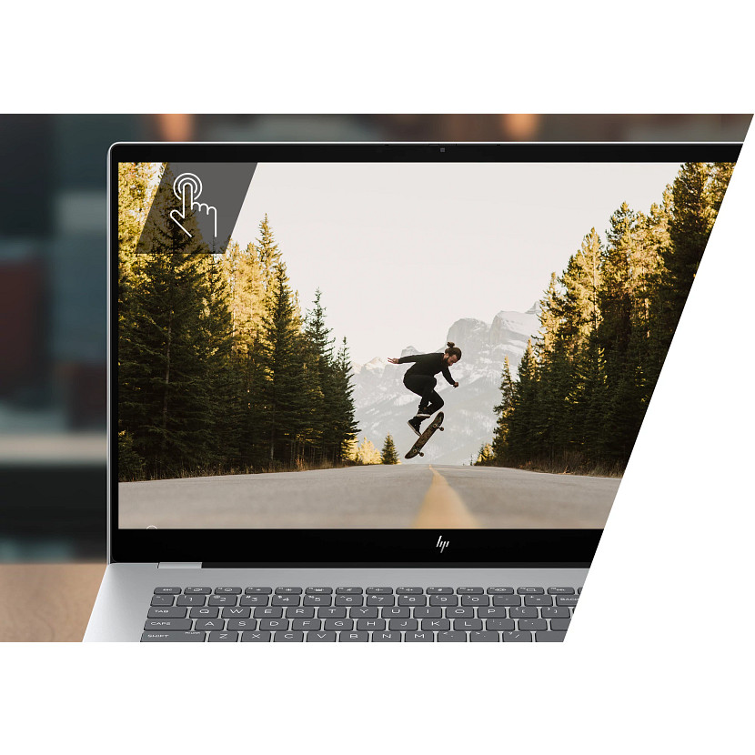 Laptop wyświetla deskorolkarza w powietrzu na drodze. Drzewa wzdłuż drogi. Klawiatura i ramka laptopa widoczne.