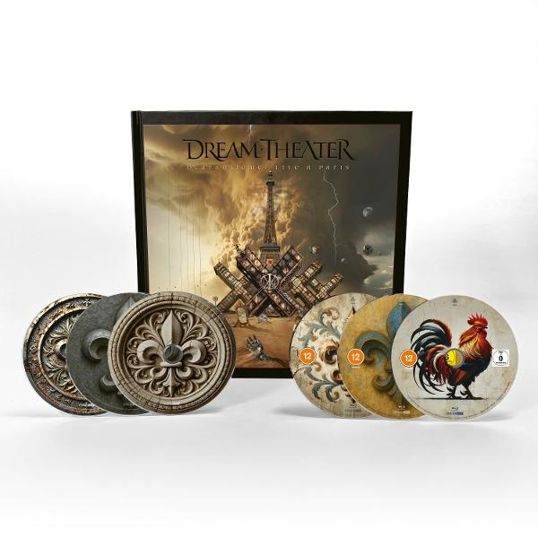 Dream Theater CD-Set. Cover zeigt Eiffelturm. CDs zeigen Fleur-de-Lis und einen Hahn. Dekorative runde Objekte davor.