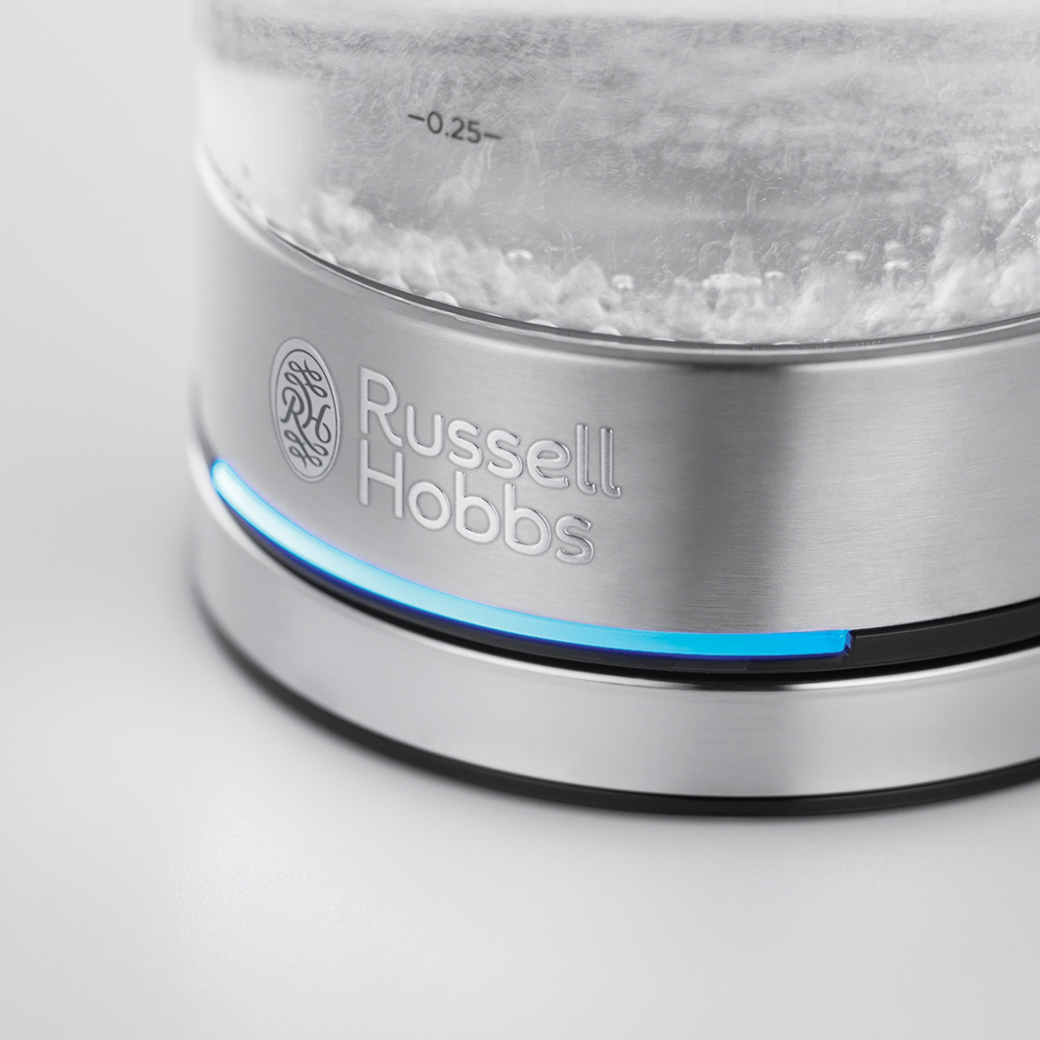 Un primo piano di un bollitore elettrico Russell Hobbs. Acqua bollente all'interno. Base in acciaio inox con luce blu.
