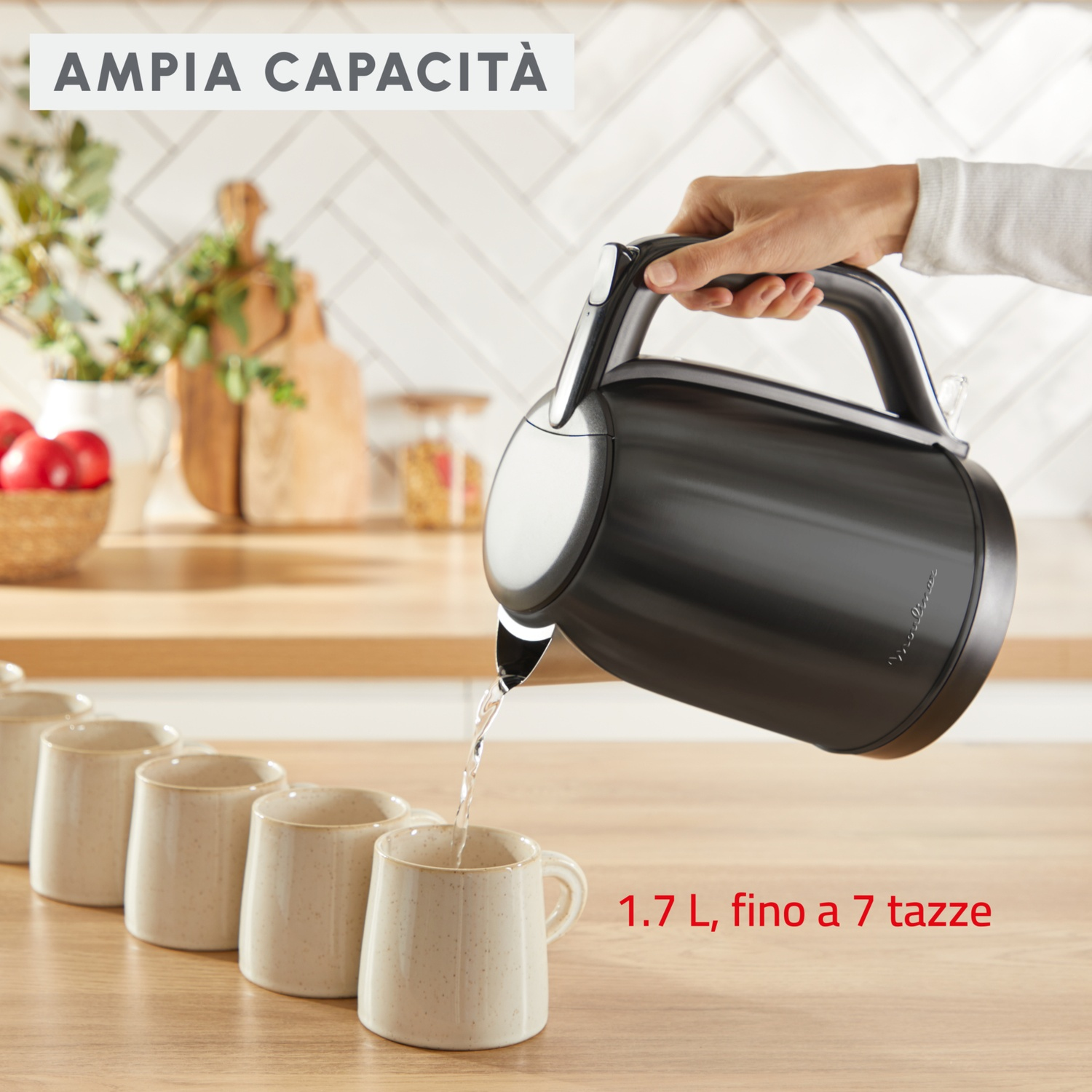 Un bollitore nero versa acqua in una tazza beige. Altre tazze sono in fila. Testo: '1.7 L, fino a 7 tazze'.