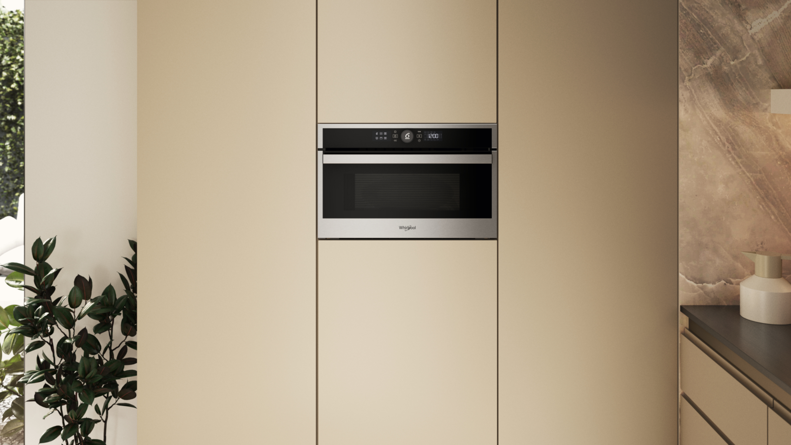 Wbudowana kuchenka mikrofalowa Whirlpool w szafce kuchennej. Drzwi szafki są beżowe. Po lewej stronie znajduje się roślina.