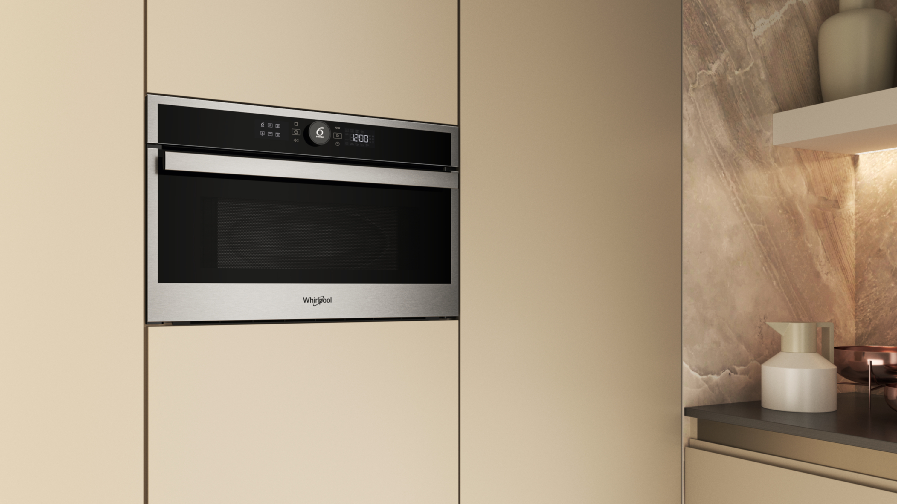 Kuchenka mikrofalowa ze stali nierdzewnej jest wbudowana w jasnobeżową szafkę. Z prawej strony znajduje się półka z białym dzbanem.