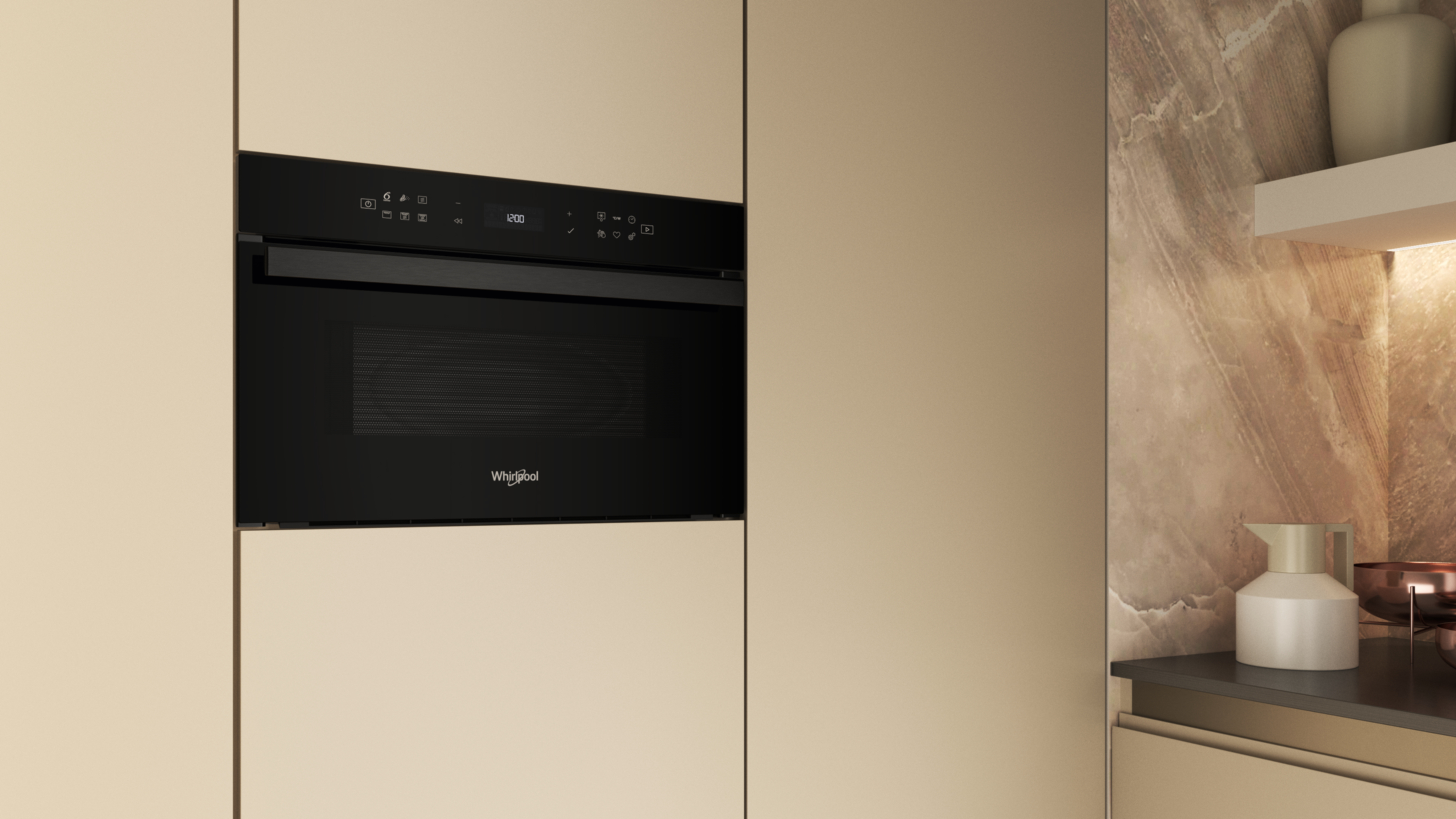 Czarna kuchenka mikrofalowa Whirlpool jest wbudowana w beżową szafkę kuchenną. Z prawej strony marmurowa ściana i półka z dzbanem.