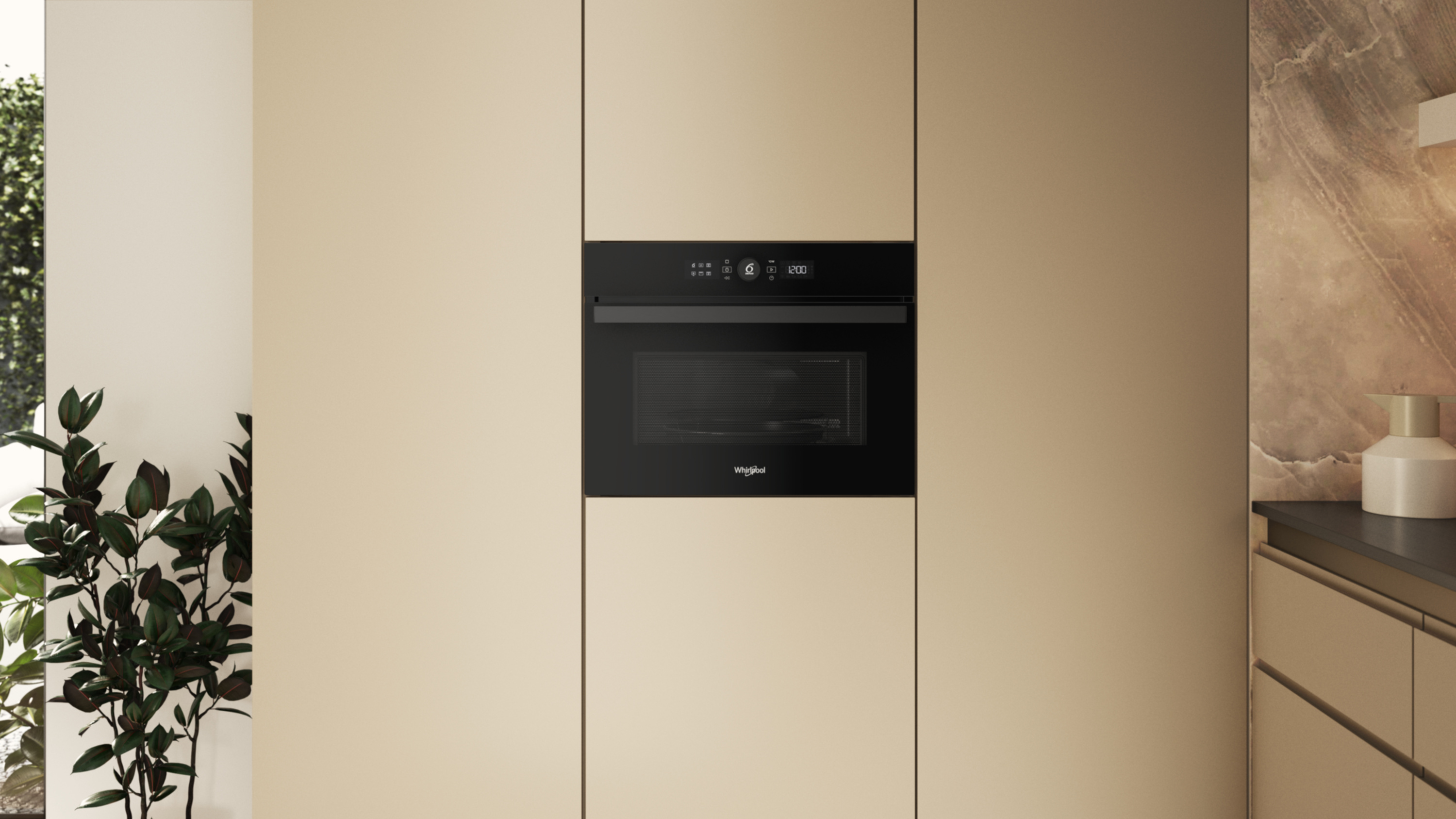 Czarna kuchenka mikrofalowa Whirlpool jest wyśrodkowana na beżowej szafce. Zielone liście widoczne po lewej stronie.
