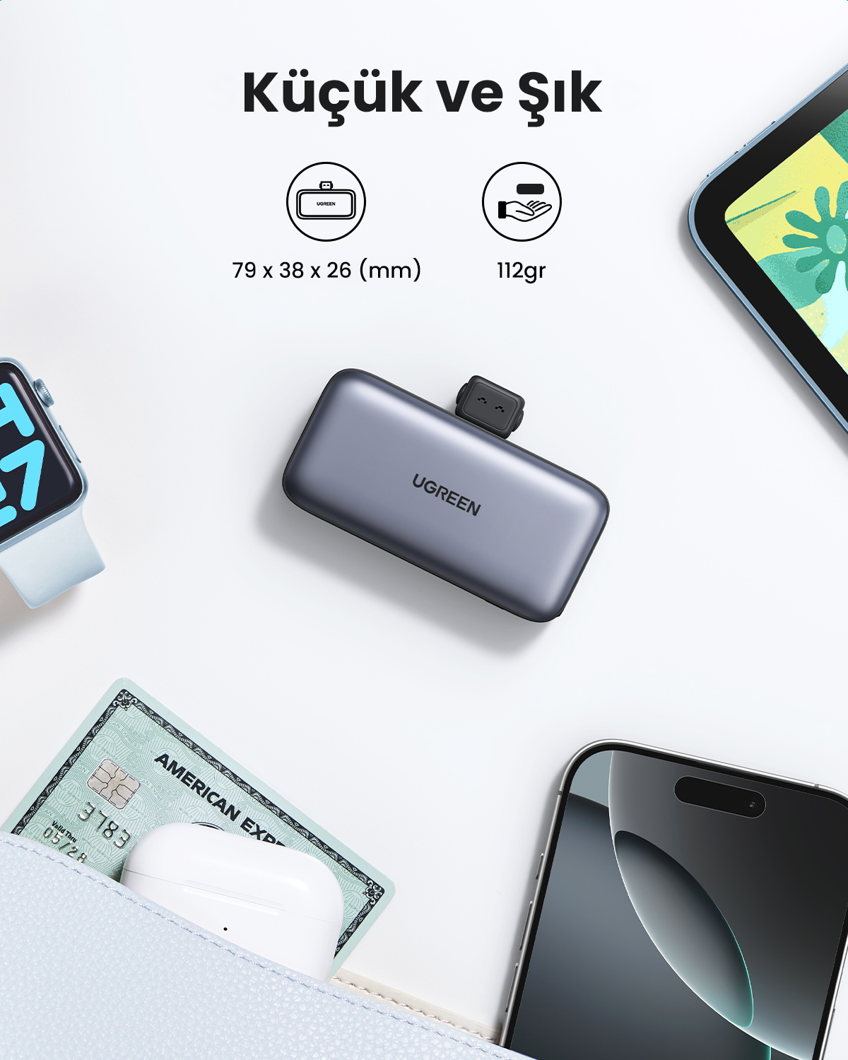 Merkezde gri bir UGREEN cihazı var. Beyaz bir yüzey üzerinde tablet, telefon, saat, kredi kartı ve kulaklıklarla çevrili. Metin: Küçük ve Şık.