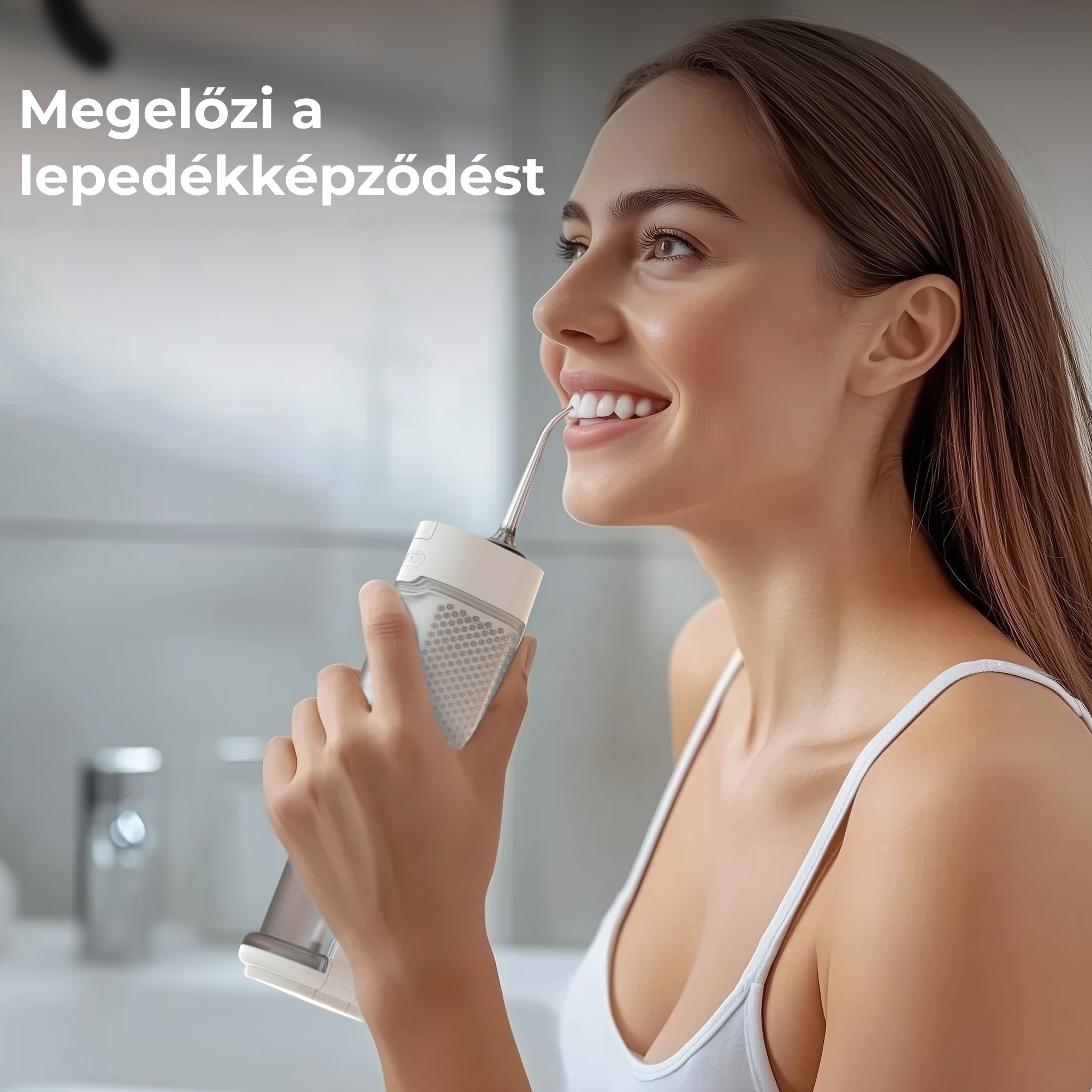 Egy nő fogászati szájzuhanyt használ. Mosolyog, miközben a készüléket a fogaihoz tartja. Fehér trikó.