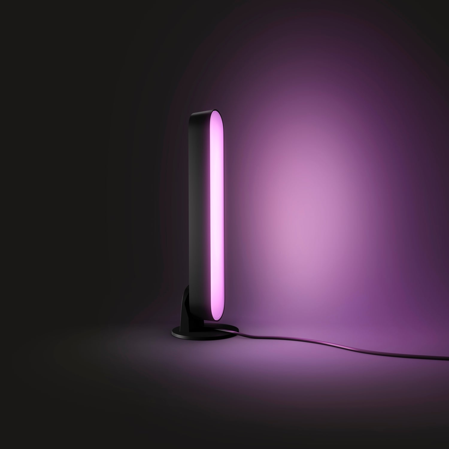 Una luce nera e rosa è accesa, che proietta un bagliore rosa su uno sfondo viola sfumato. Un cavo nero è collegato alla luce.