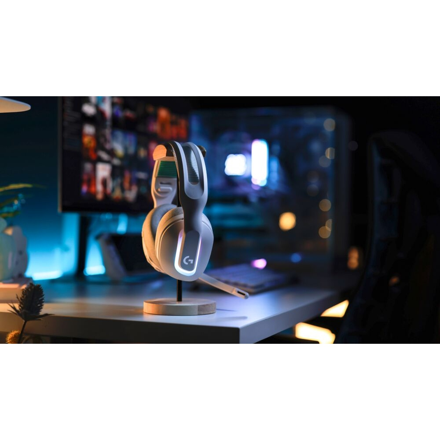 Cuffie da gaming bianche su supporto in legno, scrivania, monitor sullo sfondo. Case PC e tastiera visibili. Luce scarsa.