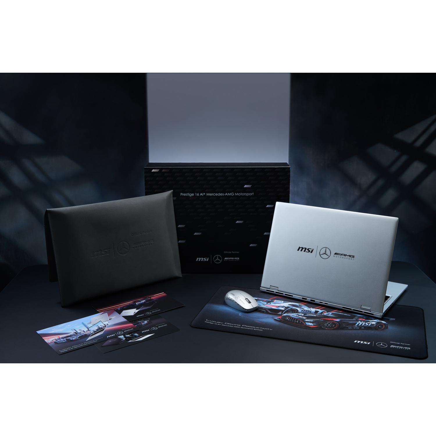 Laptop, mouse, mousepad with a car design, black case, and cards on a black table. The laptop is open, and the background is dark.