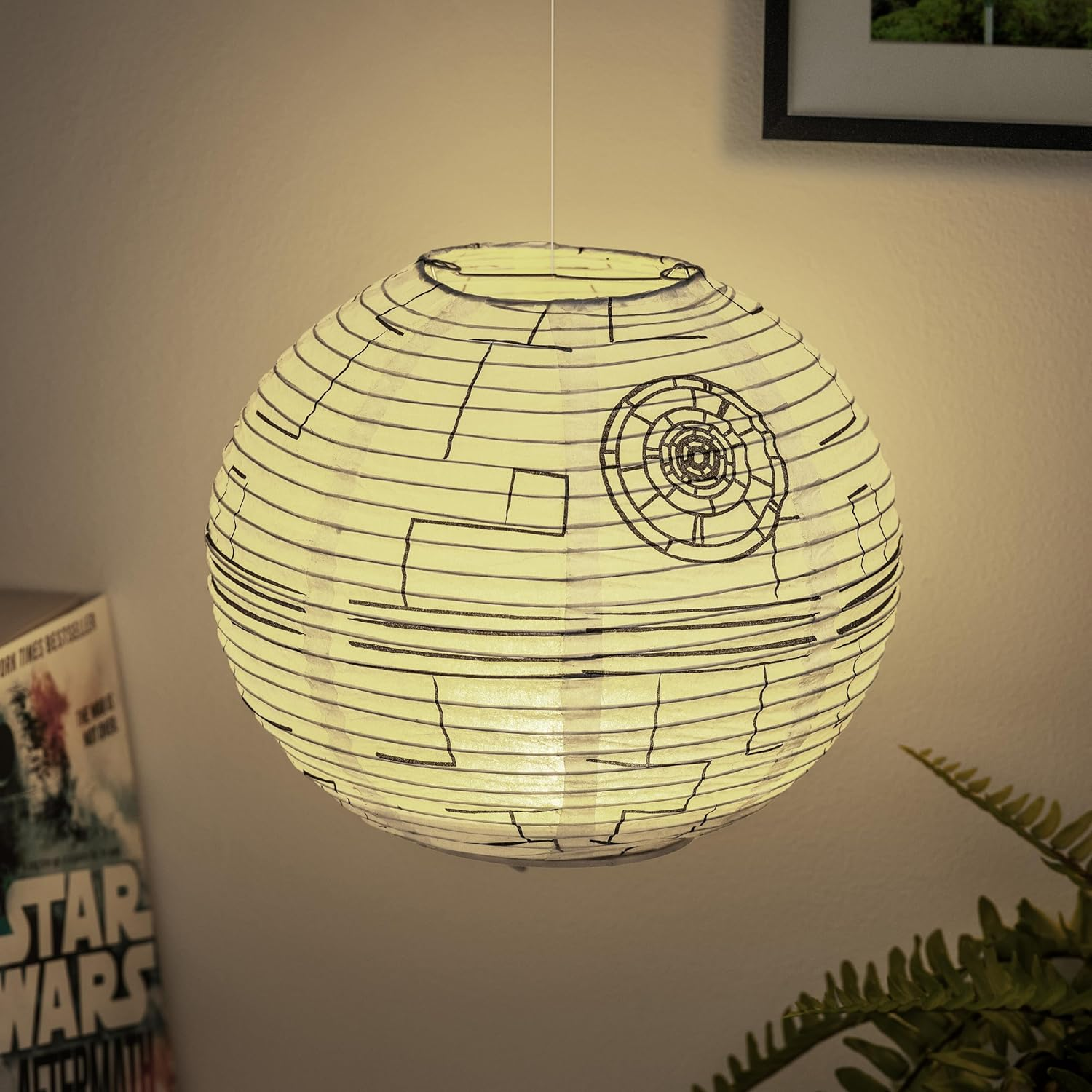 Egy Halálcsillag alakú lámpa lóg a mennyezetről. Egy Star Wars könyv látható. Egy páfrány a jobb alsó sarokban.