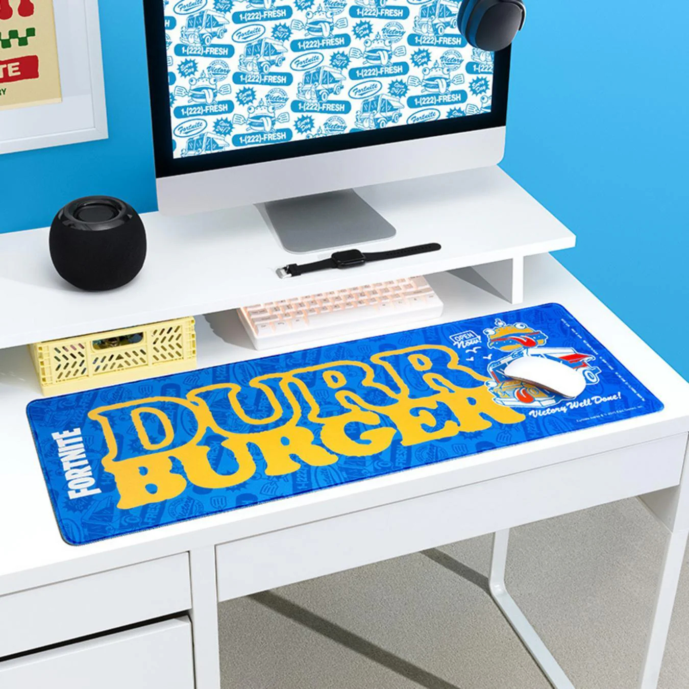 Asztal, számítógéppel, hangszóróval és egérpaddal. Az egérpadon a 'Durr Burger' felirat, rajta egy fehér egérrel.