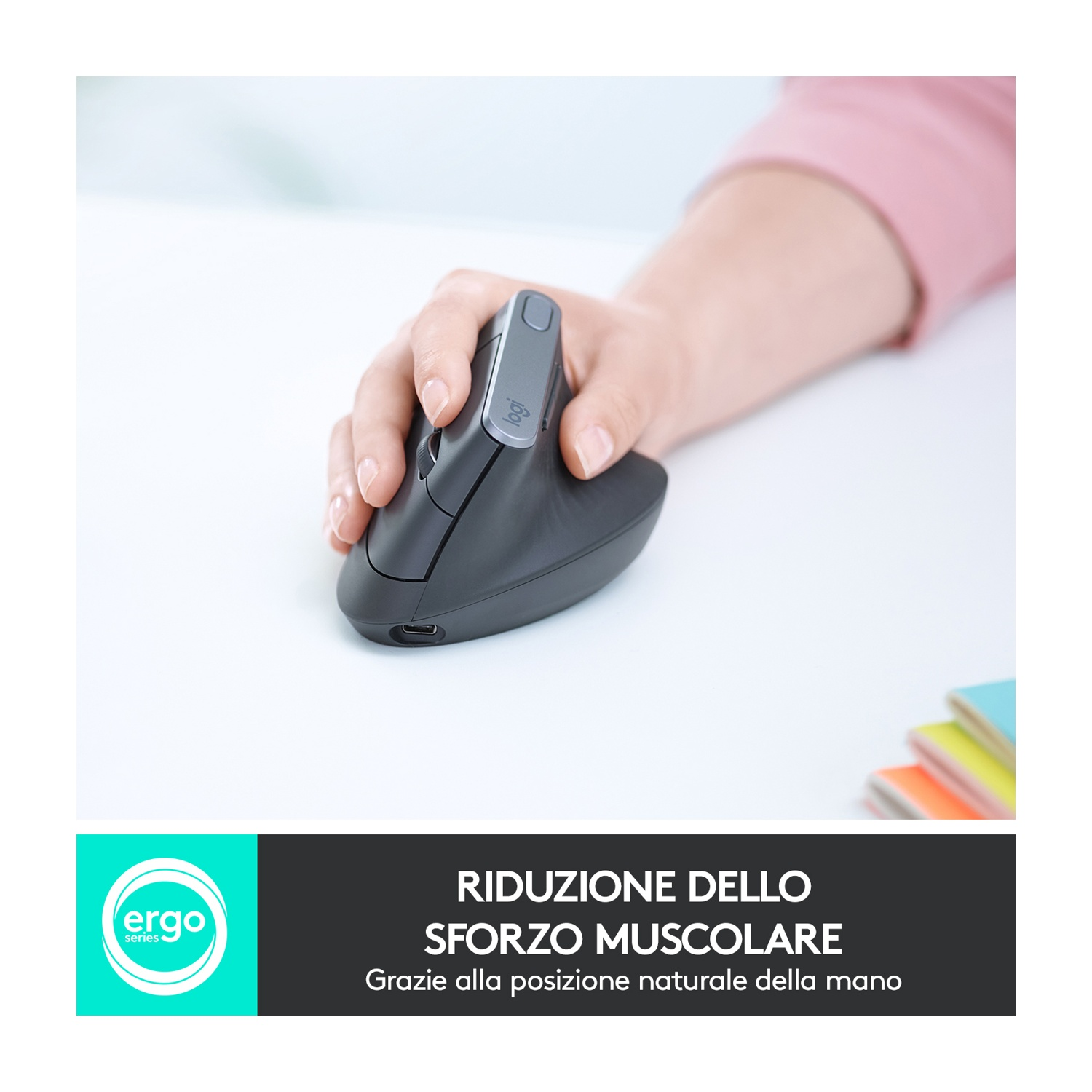 Una mano tiene un mouse verticale grigio scuro su una scrivania bianca. È visibile un braccio con manica rosa. Il mouse ha il logo Logitech.