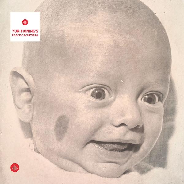 Graustufenbild eines Babygesichts mit überraschtem Ausdruck. Auf der Wange befindet sich ein dunkles Muttermal. Text: Yuri Honing's Peace Orchestra.