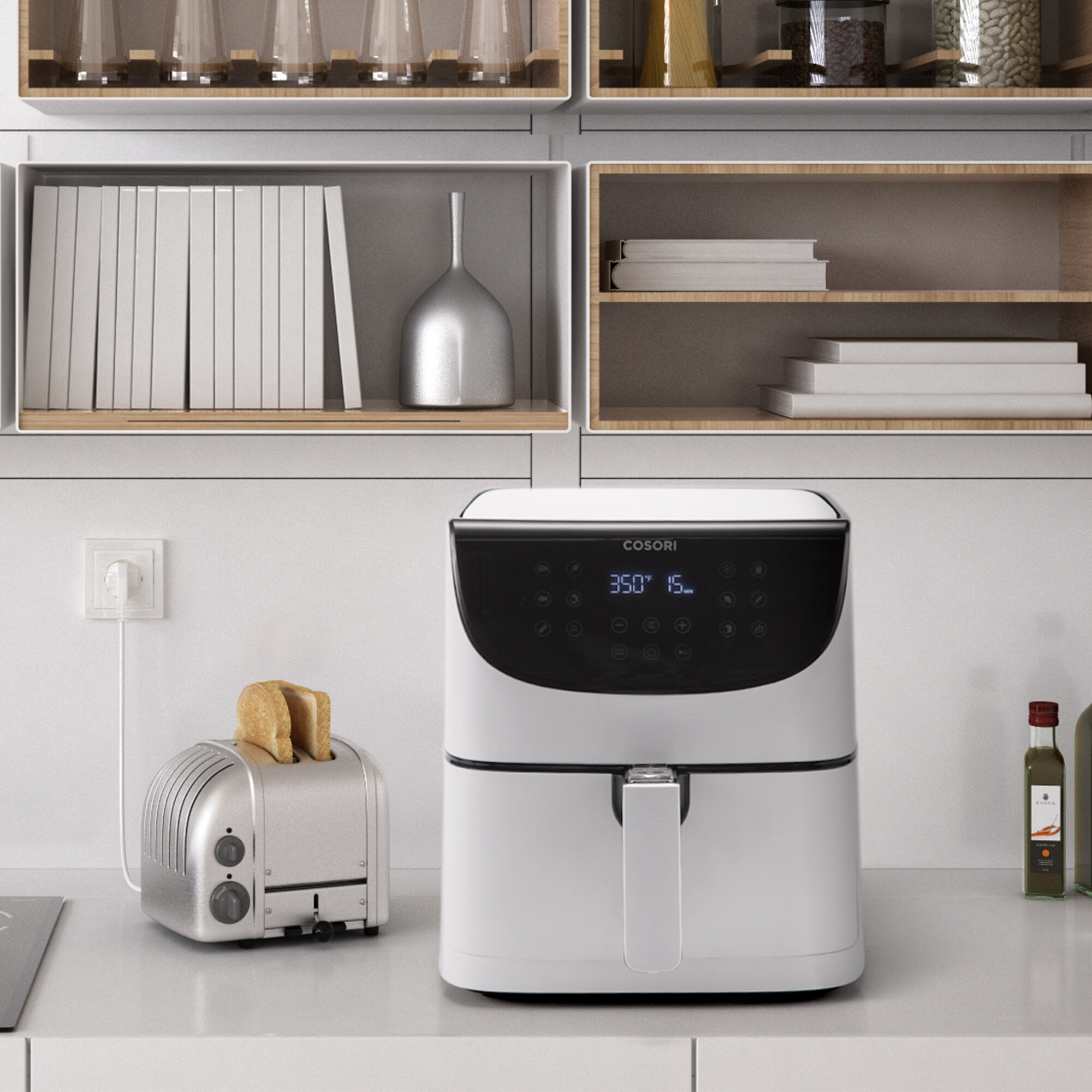 Scena kuchenna. Biała frytkownica i toster z chlebem stoją na blacie. Półki nad nimi zawierają przedmioty.