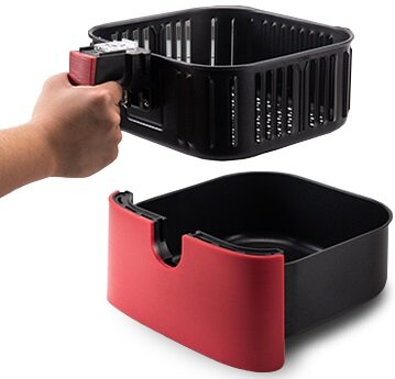 Ręka trzyma czerwony uchwyt kosza do frytkownicy powietrznej nad czarnym pojemnikiem. Kosz jest czarny z pionowymi szczelinami.