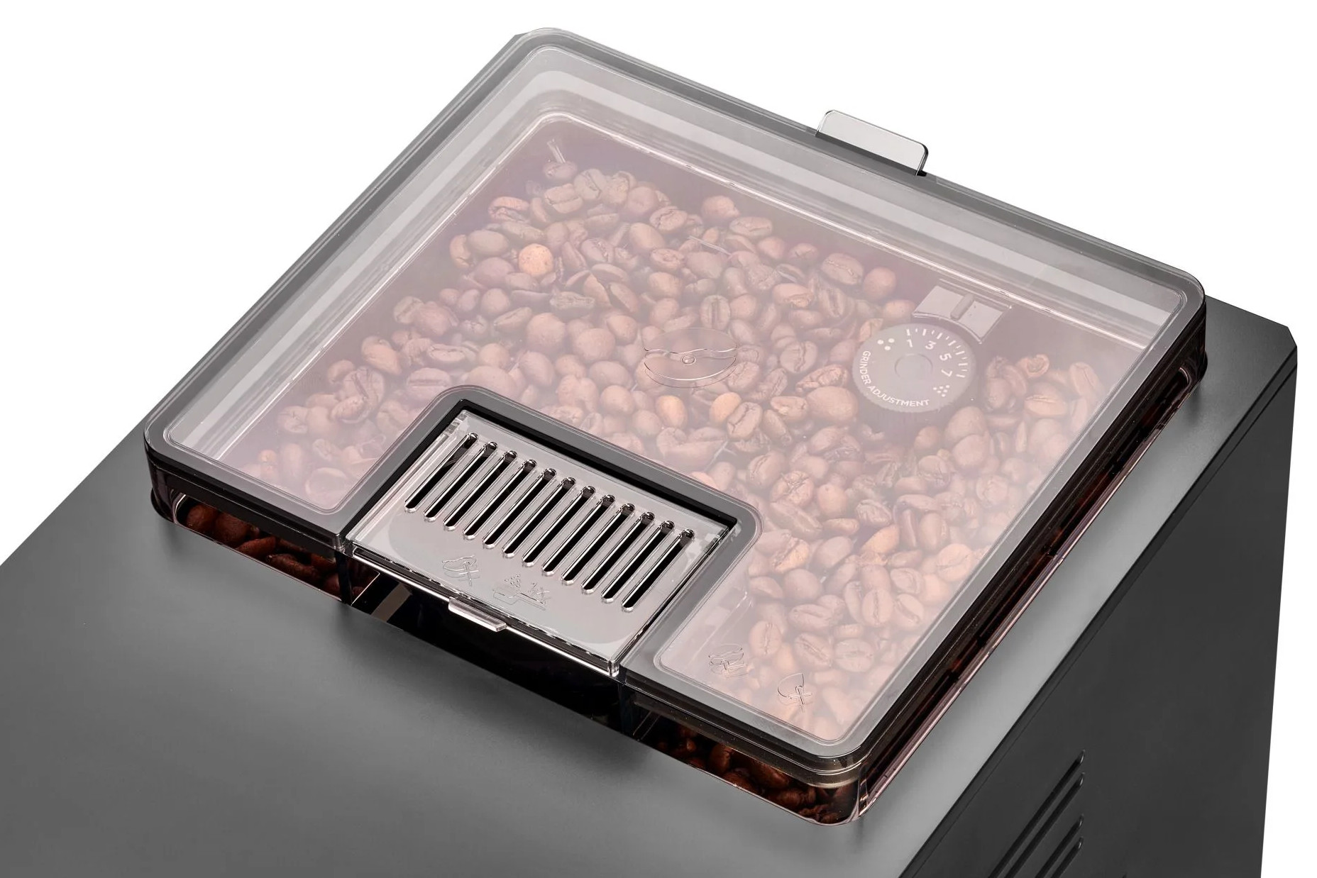 Pojemnik na ziarna w ekspresie do kawy. Przezroczysta pokrywa z ziarnami kawy. Widoczne pokrętło regulacji mielenia. Srebrne metalowe części.