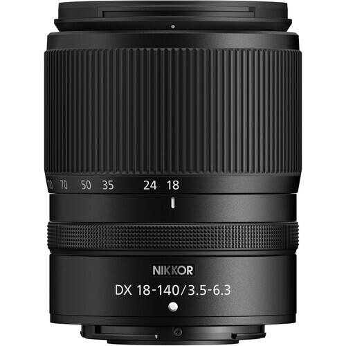 Siyah bir Nikkor DX 18-140/3.5-6.3 kamera lensi. Yivli bir namluya ve odak uzaklığı işaretlerine sahiptir. Lens yenidir.
