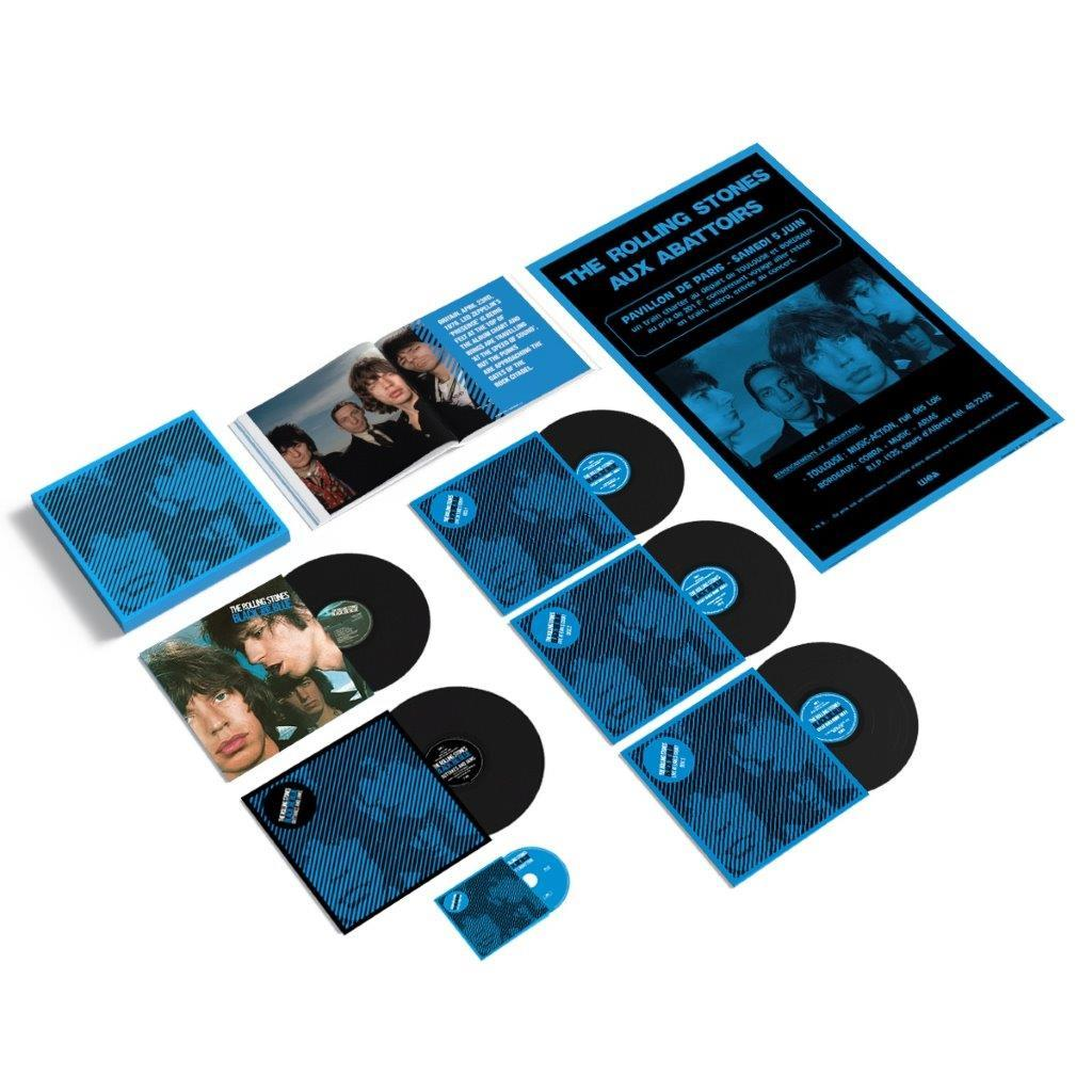 Rolling Stones-Platten und Konzertflyer auf weißer Oberfläche. Alben, CDs und Werbematerial in Blau- und Schwarztönen.