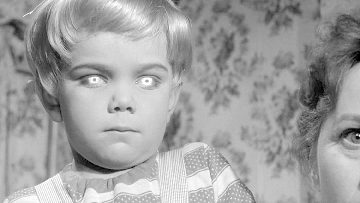 Schwarz-Weiß-Bild eines Kindes mit leuchtend weißen Augen. Rechts ist eine Frau teilweise zu sehen. Blumige Tapete im Hintergrund.