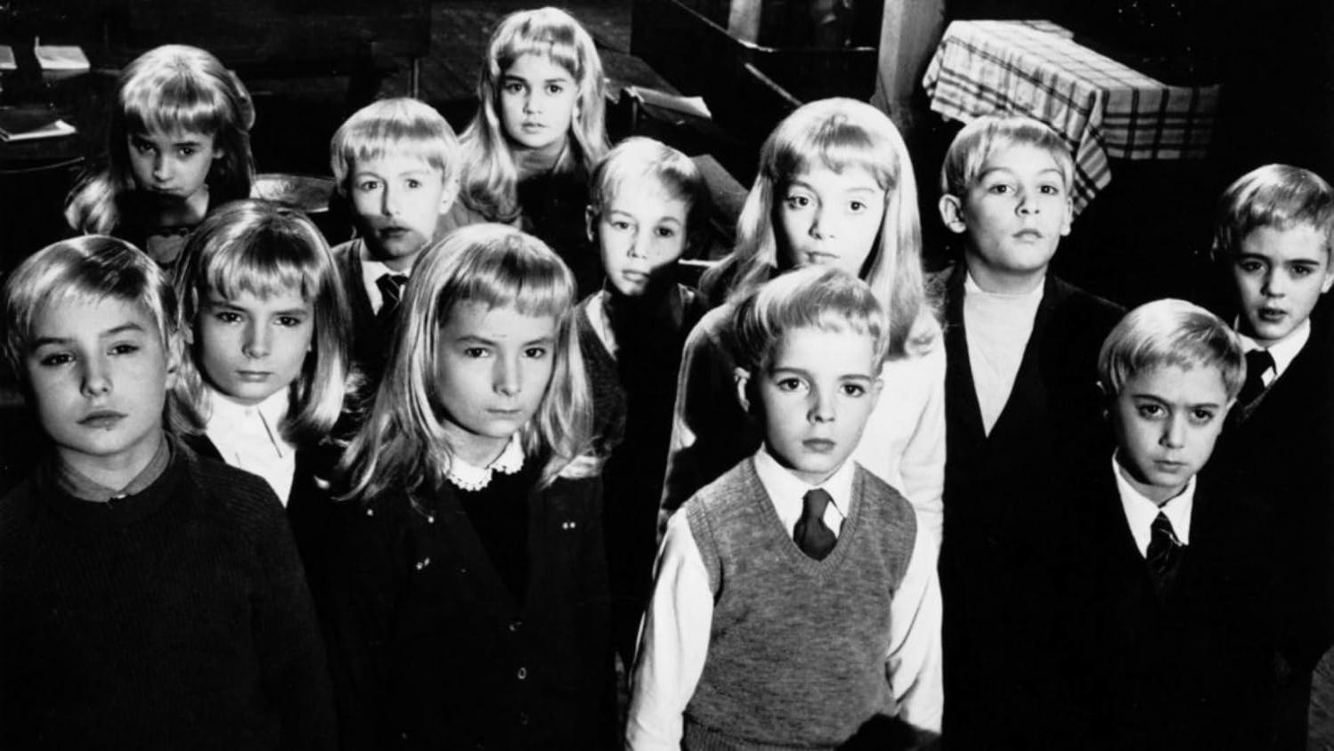 Ein Schwarzweißfoto mit einer Gruppe von Kindern mit ähnlichen Frisuren, die in die Kamera schauen. Im Hintergrund ist ein Tisch zu sehen.