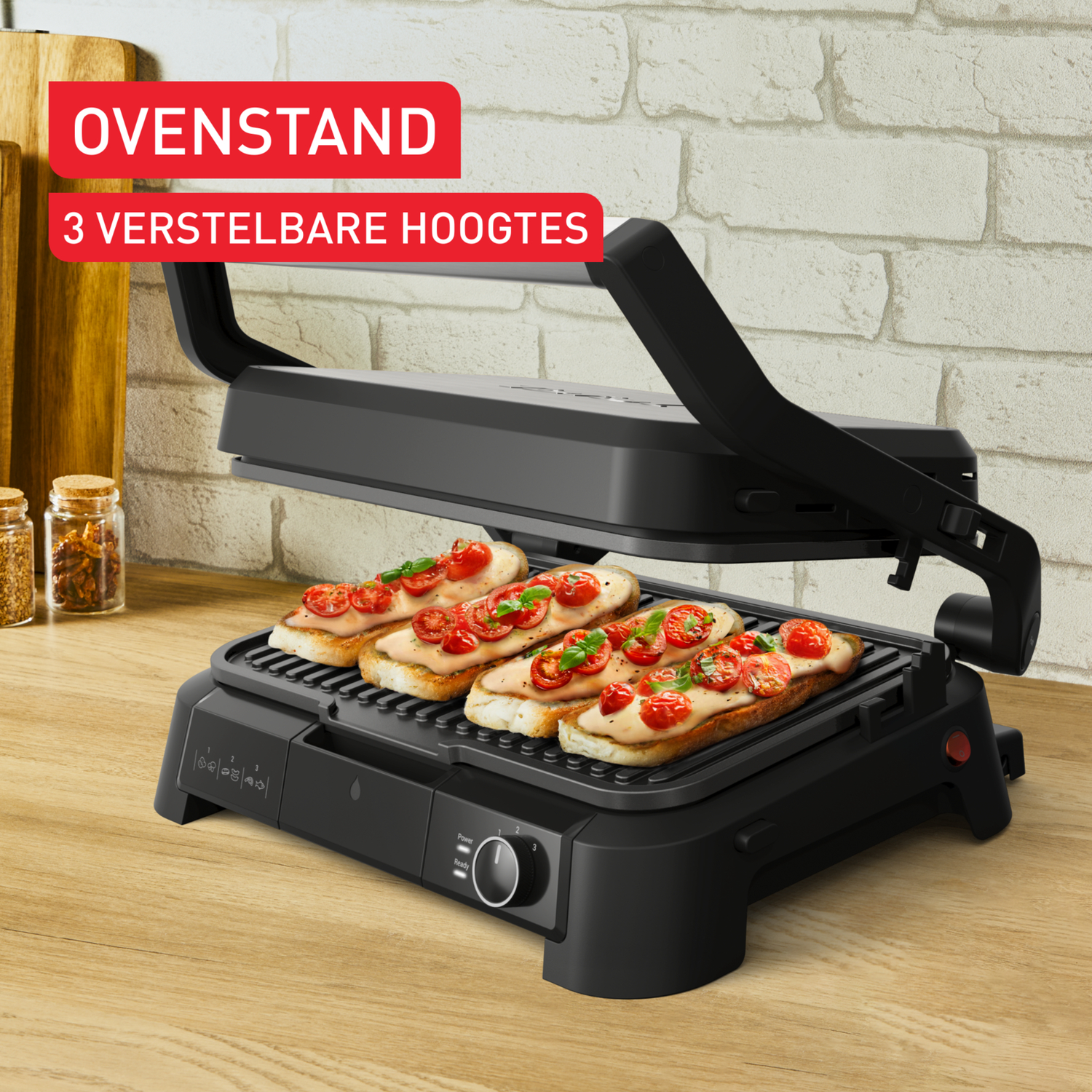 Un grill noir avec du pain grillé garni de tomates. Le texte en haut indique 'Ovenstand' et '3 verstelbare hoogtes'.