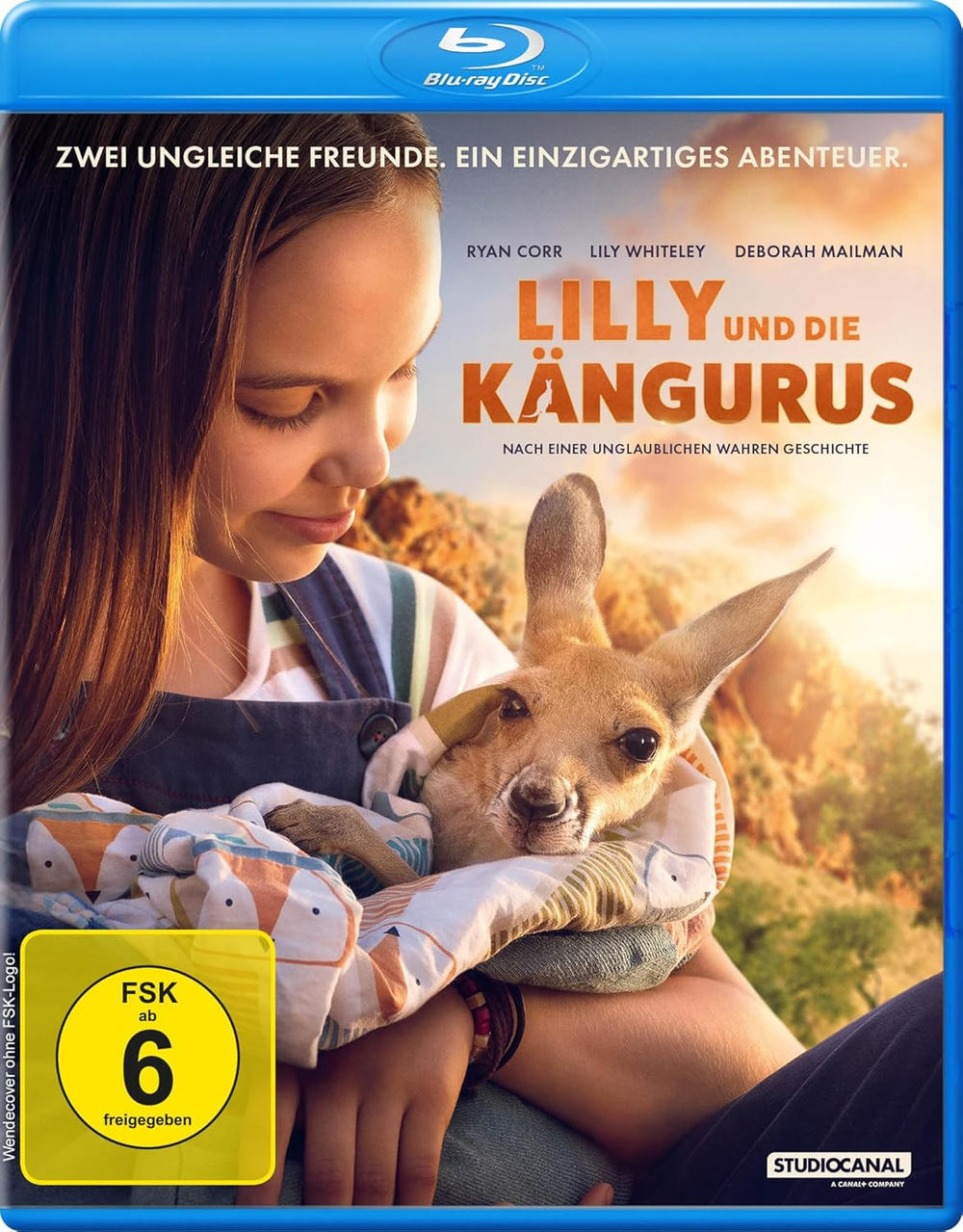 Ein Mädchen hält ein in eine Decke gewickeltes Känguru. Das Blu-ray-Cover hat Text auf Deutsch. Das Cover sagt Lilly und die Kängurus.