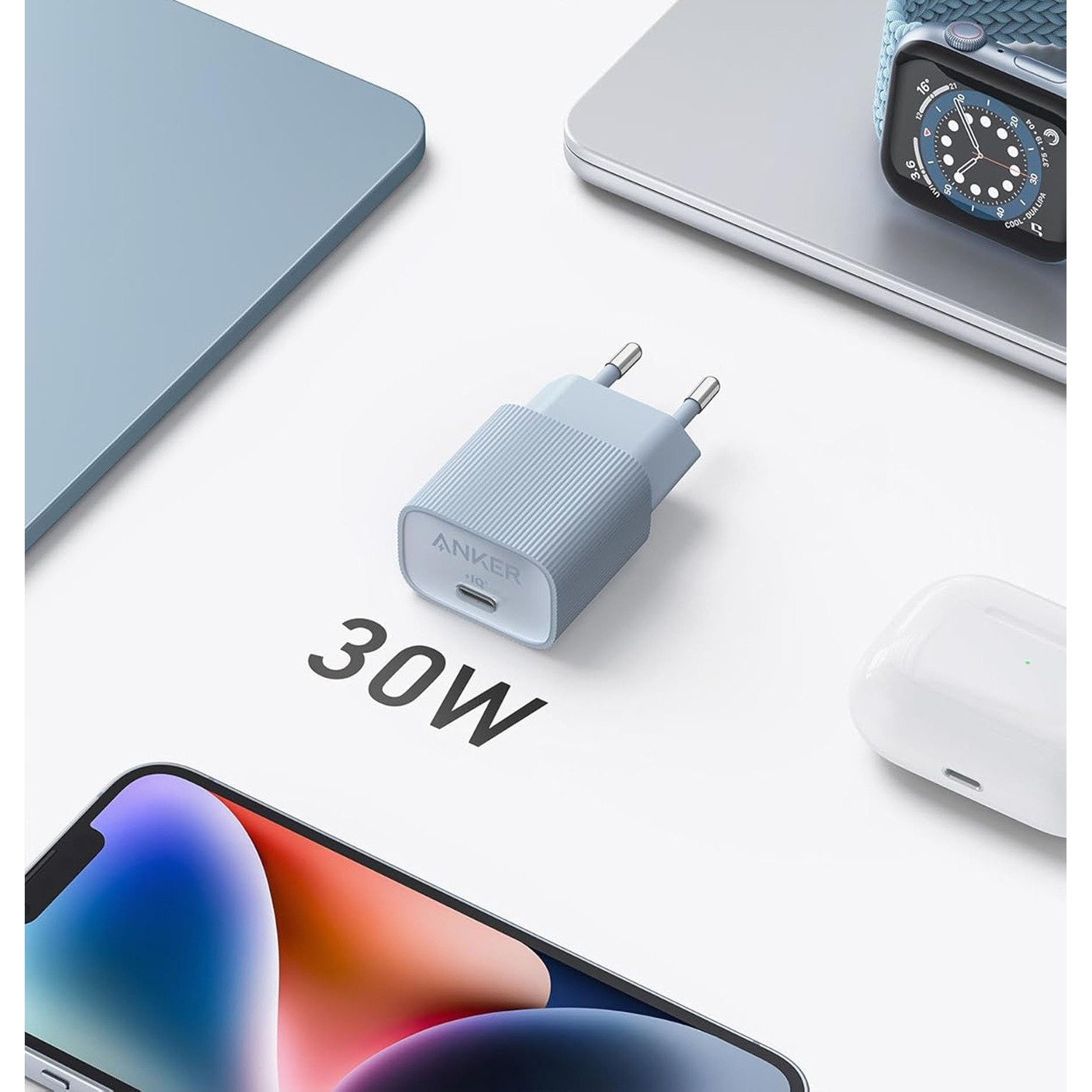 Un caricatore Anker blu con testo 30W, circondato da un laptop, orologio, telefono e AirPods su una superficie bianca.