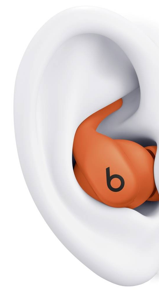 Zbliżenie pomarańczowej słuchawki z czarnym logo 'b' wewnątrz białego modelu ucha. Model ucha jest lekko pochylony.