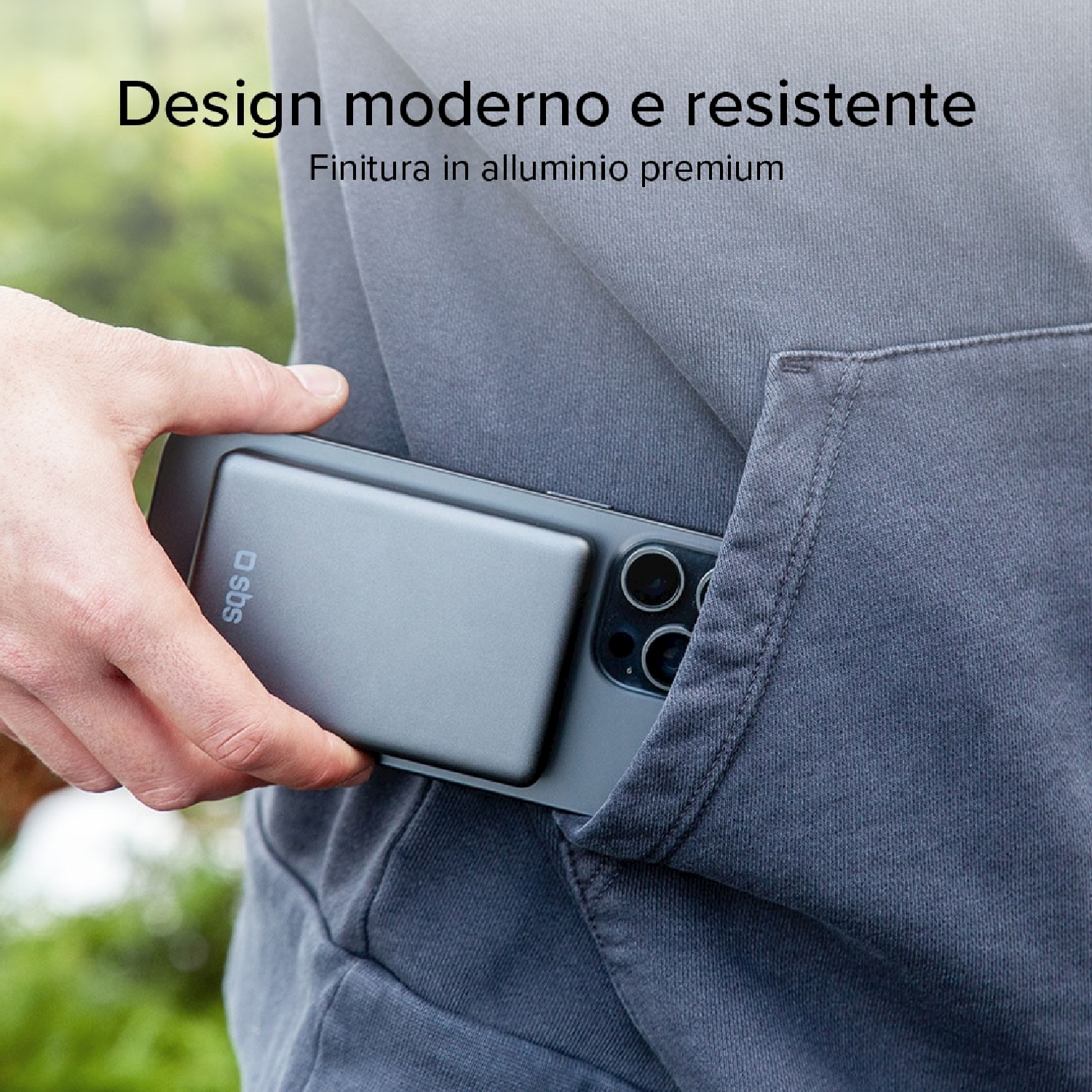 Una mano tiene un telefono con una custodia grigia in tasca. Il telefono ha più fotocamere. Lo sfondo è verde sfocato.