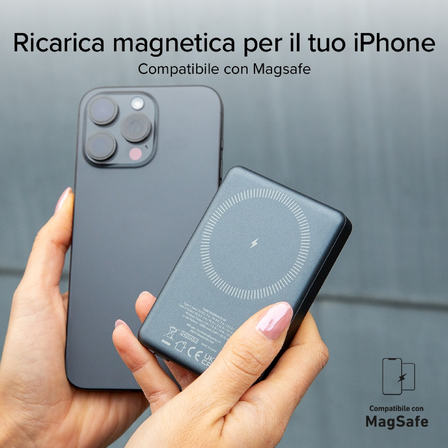 Una persona tiene in mano un iPhone nero e un caricatore magnetico. Il pad è vicino al telefono, per la ricarica.