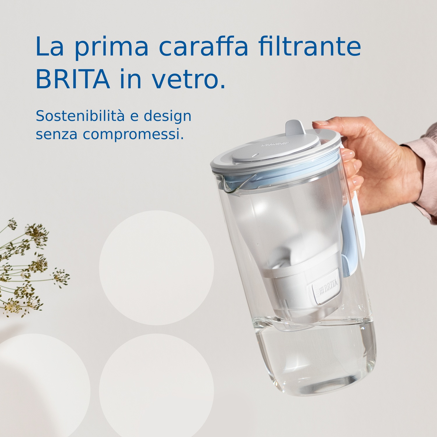 Una mano tiene una caraffa filtrante BRITA in vetro. Il testo recita: "La prima caraffa filtrante in vetro BRITA. Sostenibilità e design senza compromessi."