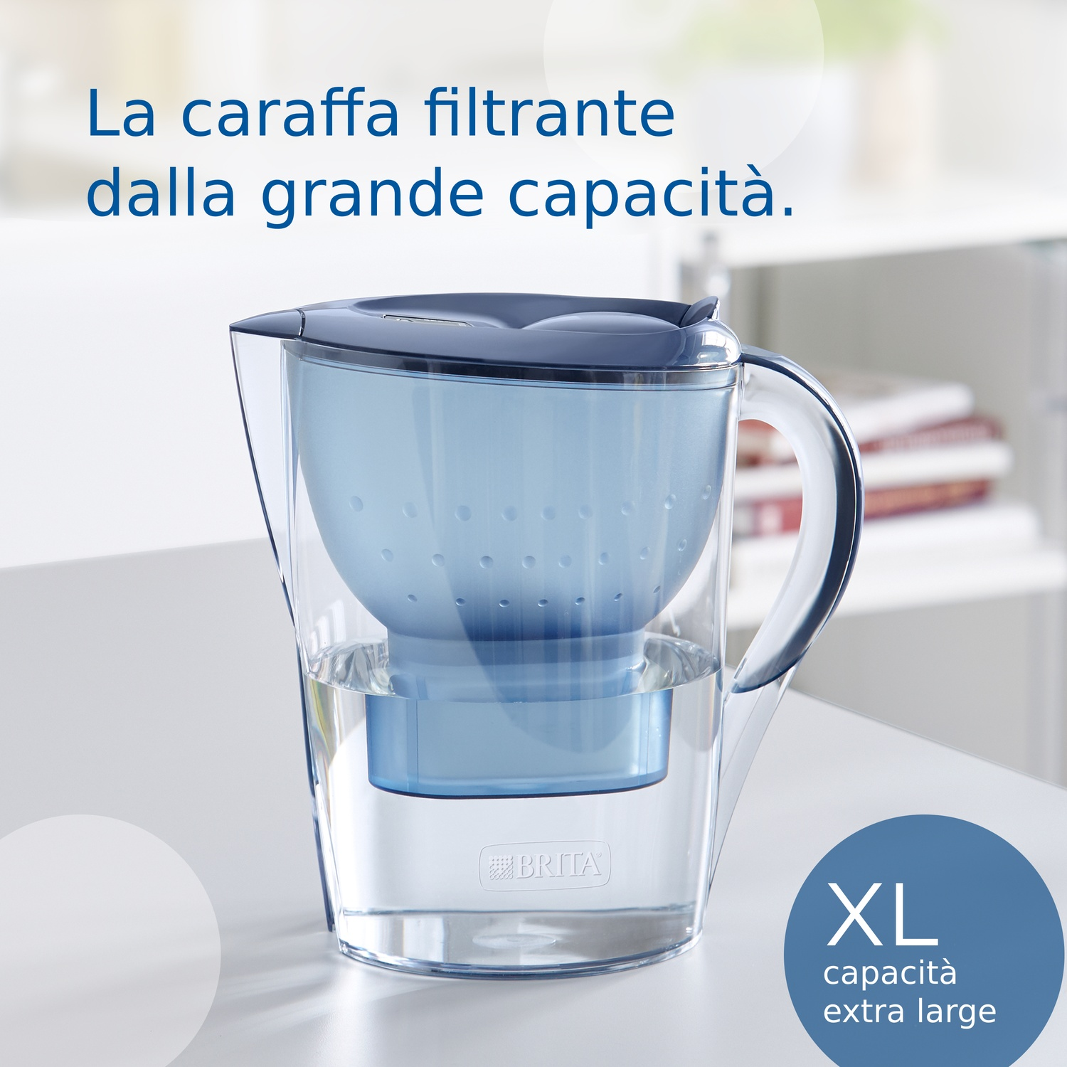 Una caraffa filtrante trasparente con dettagli blu, piena d'acqua. Testo: 'XL capacità extra large'. Sfondo: superficie bianca.